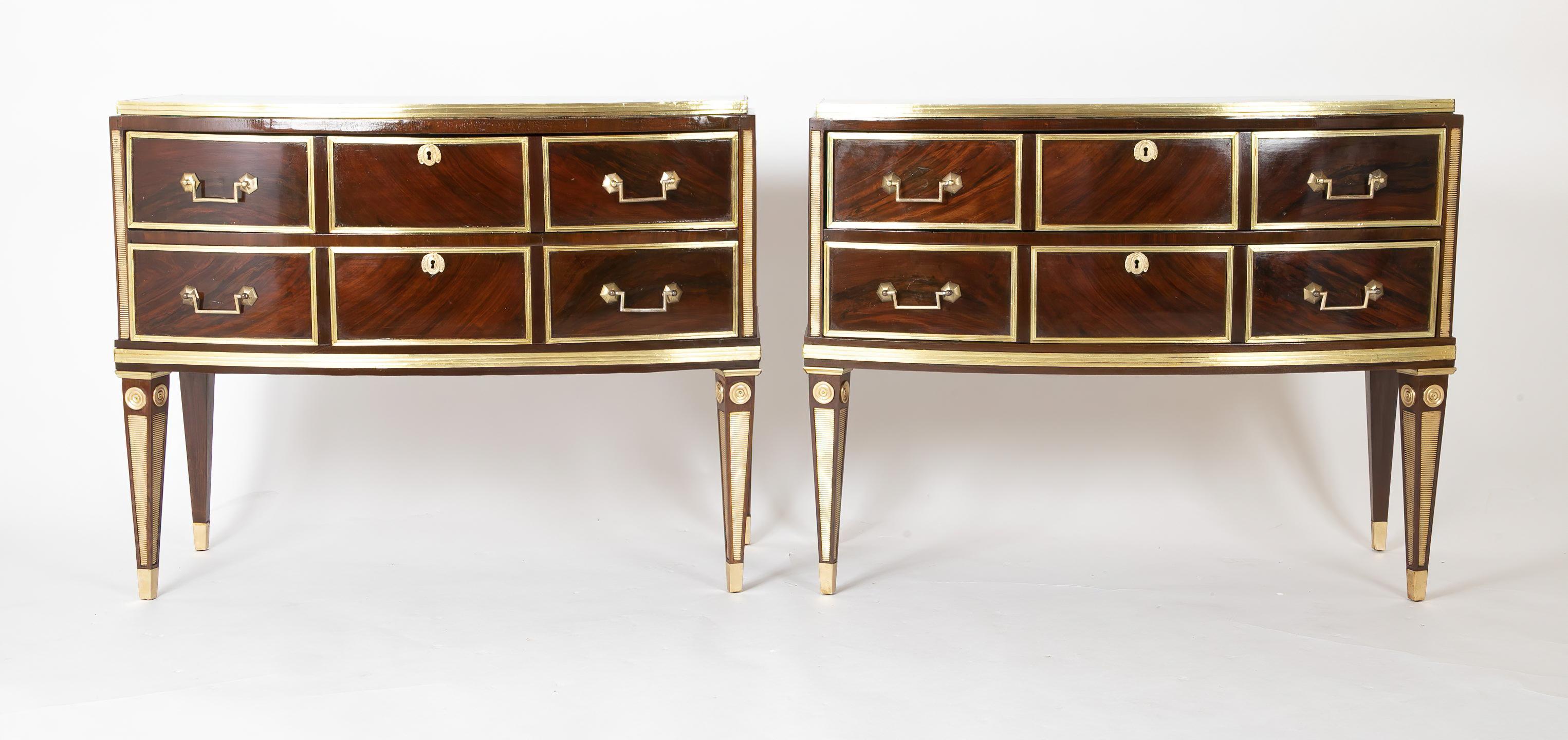 A rare pair of Russian neoclassic commodes, the figured mahogany exterior inlaid and mounted with reeded brass trim, with a stepped top and two bow front long drawers. The commodes are raised on square tapered and inlaid legs. 

Measures: 29.75