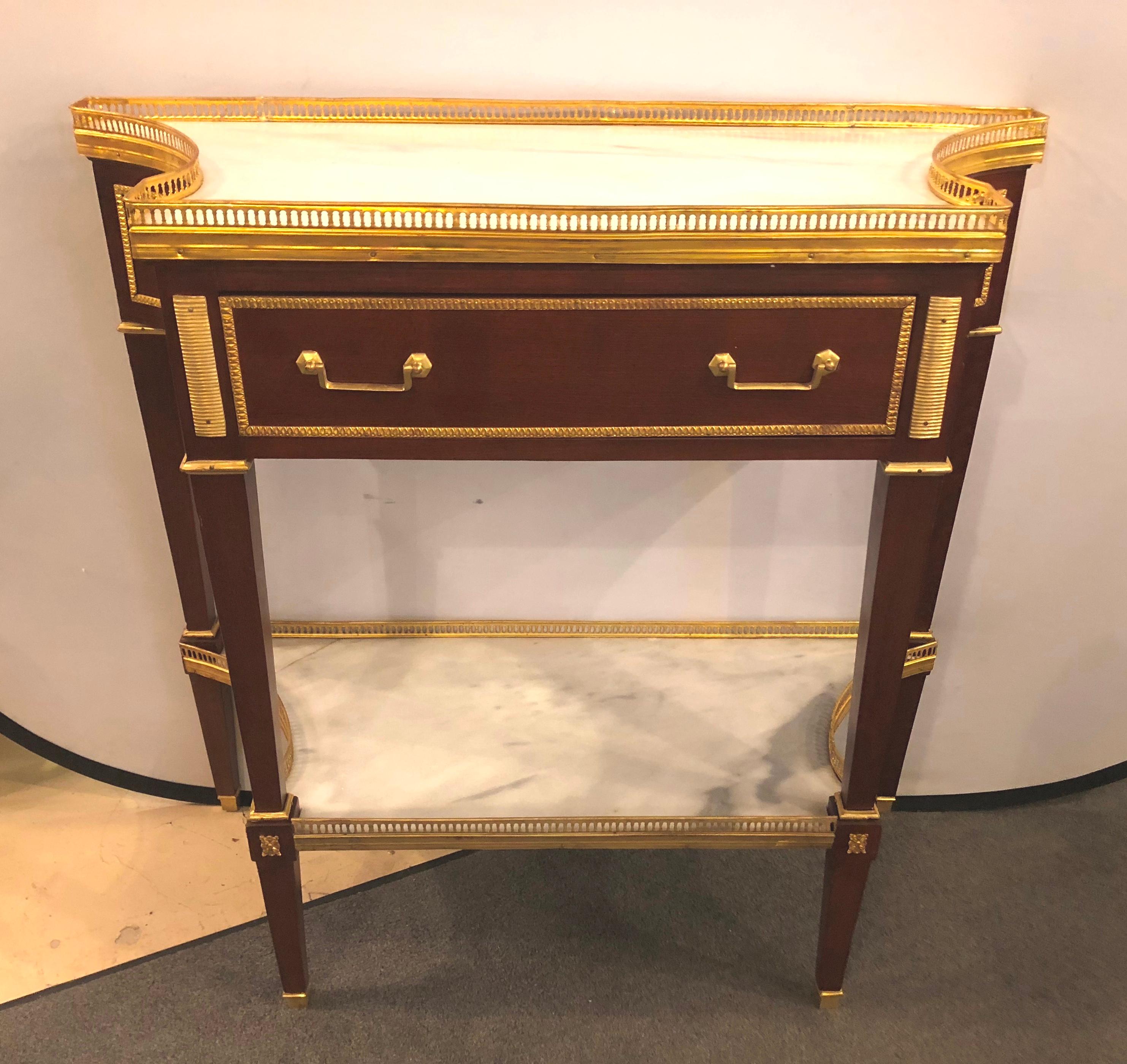 Pair of Russian neoclassical style consoles with inverted sides and marble tops. These fine Maison Jansen inspired console tables or serving tables depict the glamour of the Hollywood Regency era at its height. Each having tapering legs with bronze