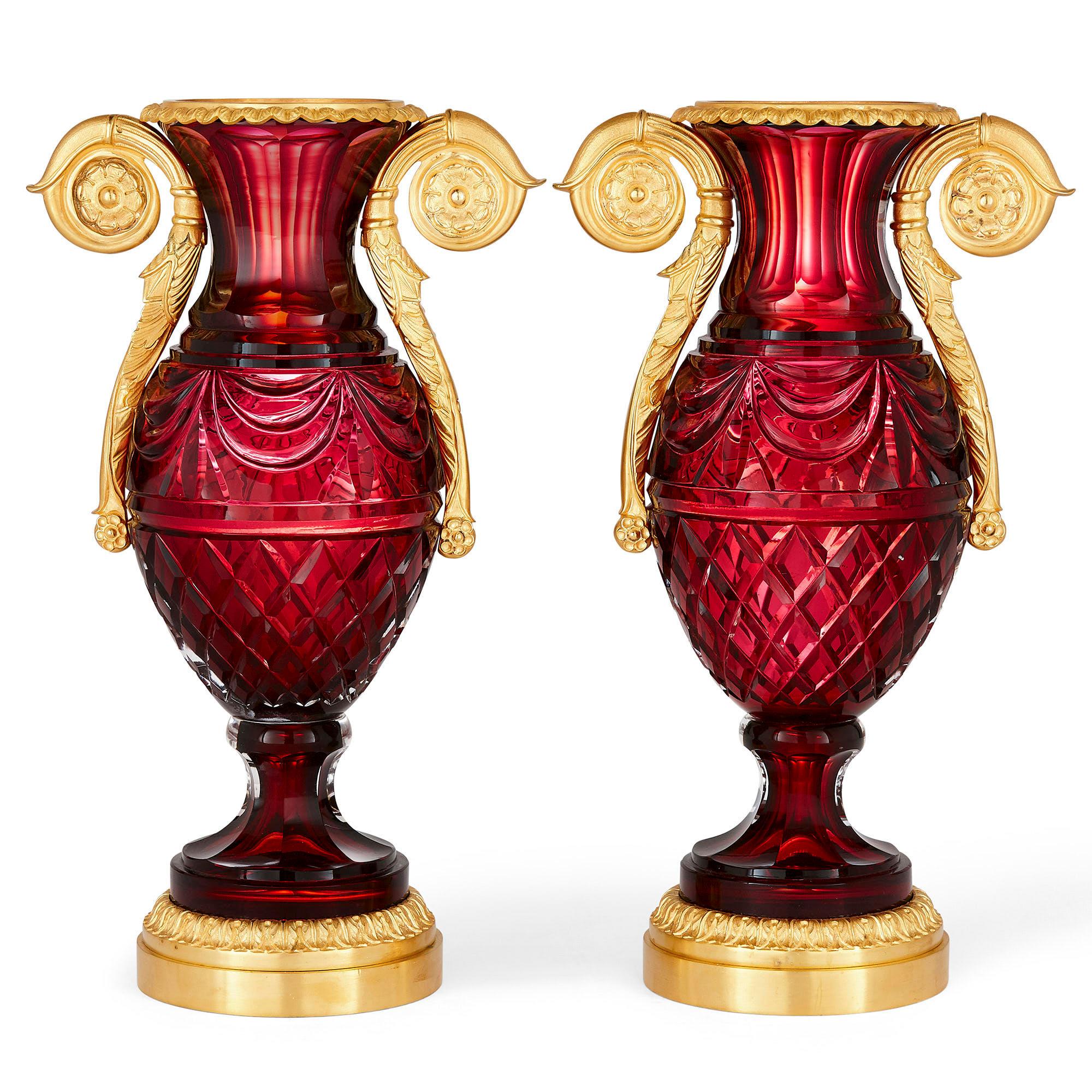 Pair of Russian neoclassical style cut glass and gilt bronze vases
Russian, 20th century
Measures: Height 38cm, width 22cm, depth 14cm

Each vase has an ovoid ruby coloured cut glass body and a flared neck. They are mounted with twin gilt bronze