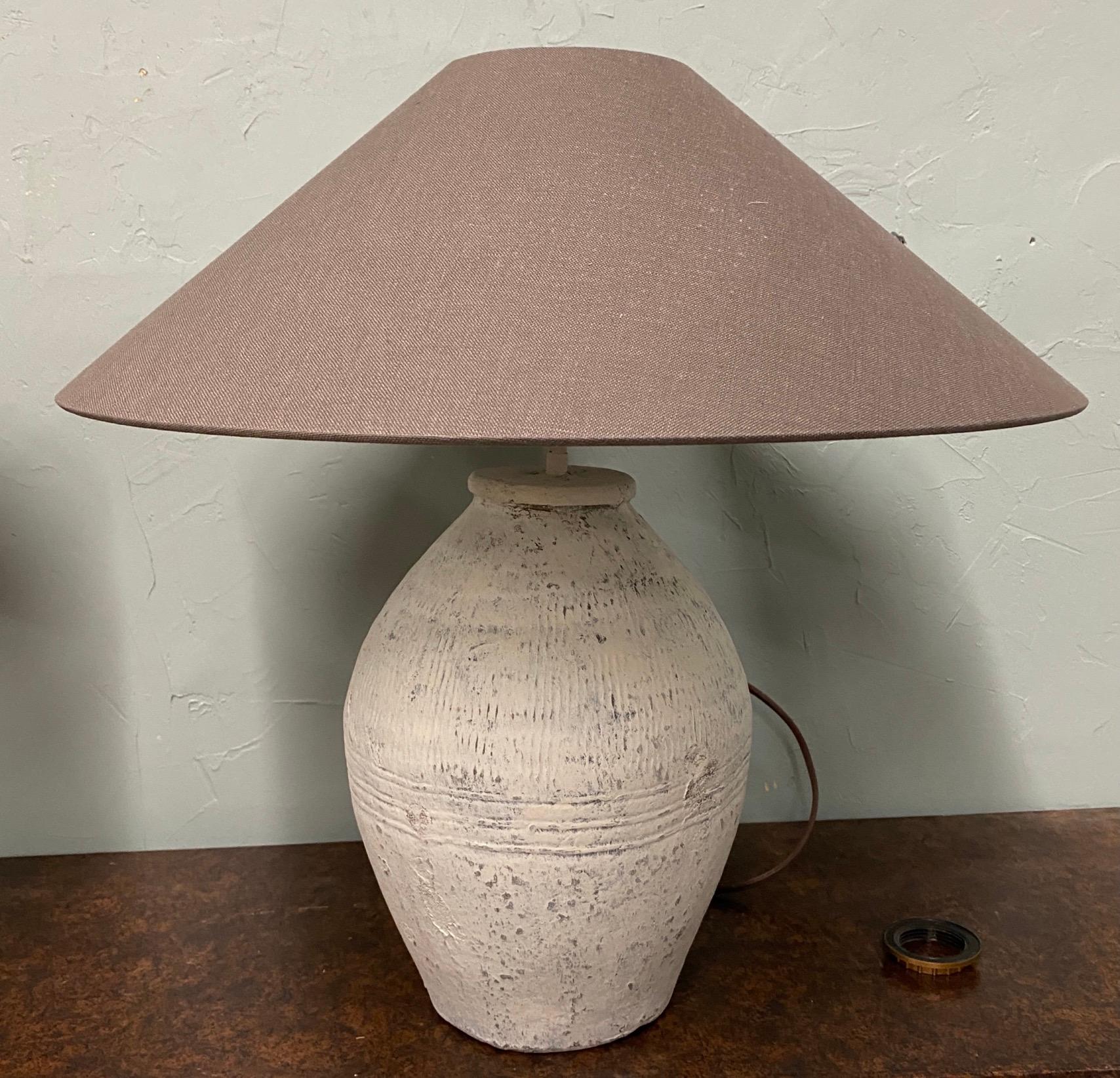 Pair of similar white painted, grey green terracotta lamp bases made from rustic vintage Chinese clay jars used for wine storage. These are not a matching pair since each of these are hand made and are not intended for decorative use. The jars are