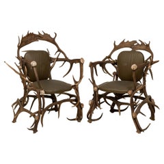 Paire de fauteuils rustiques de style continental en cuir vert olive et faux bois de cervidé