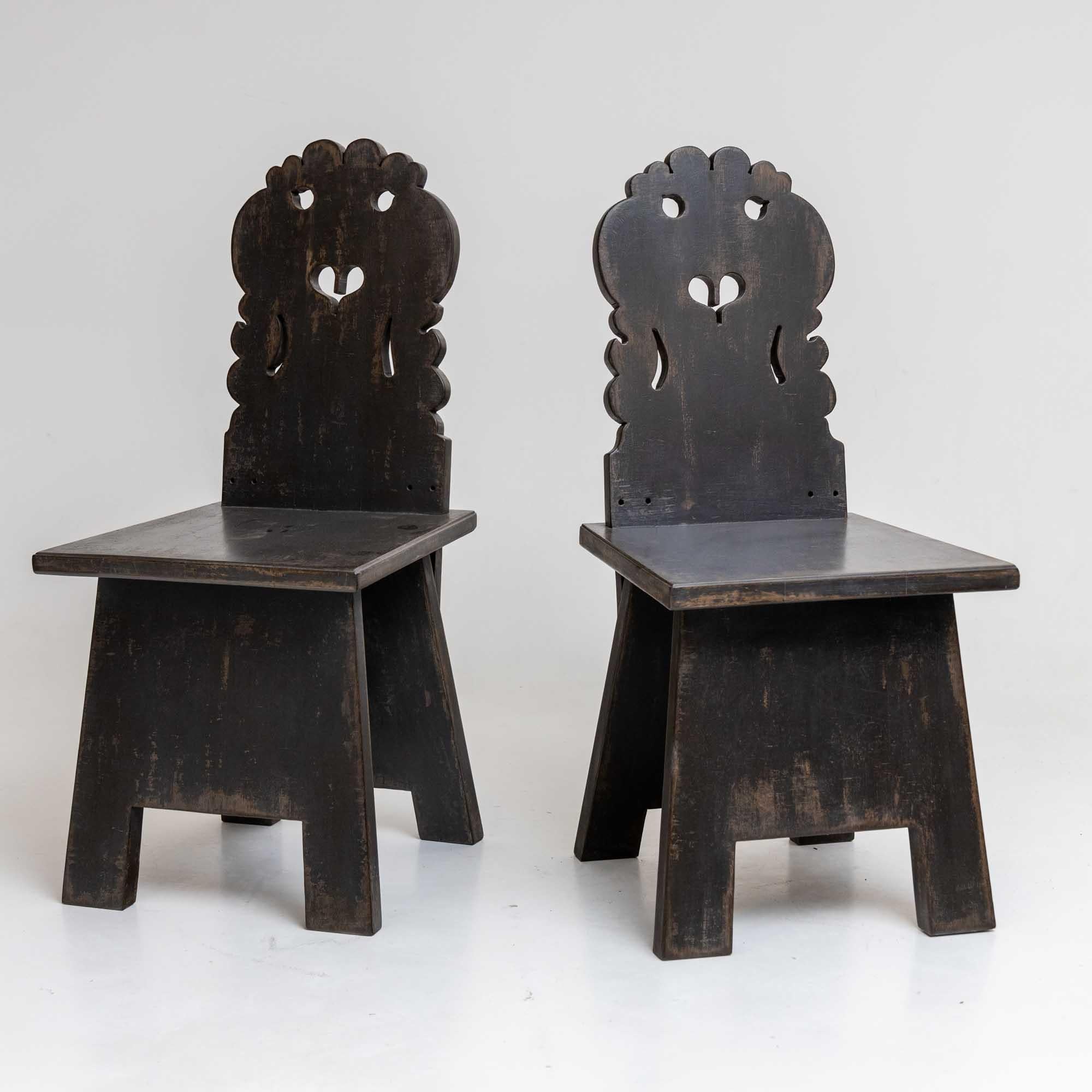 Pair of board chairs with cut-out curved backrests with a heart-shaped opening. The straight seat boards rest on closed legs. The dark gray patination is new and has been given an antique character.