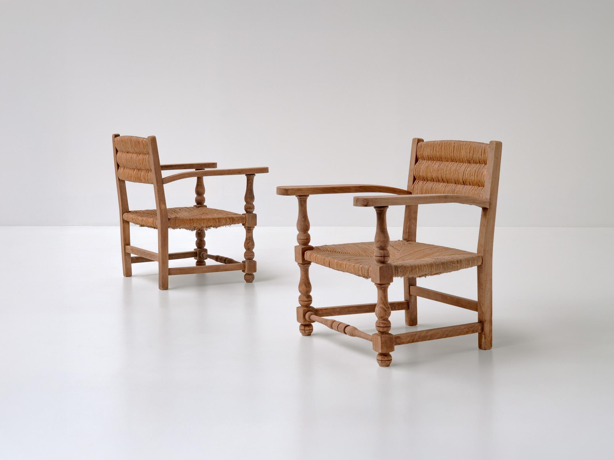 Cette élégante paire de fauteuils français dégage une sophistication tranquille grâce à un équilibre parfait entre simplicité rustique et retenue moderne. Fabriquées en bois de chêne massif avec des sièges en jonc tressé à la main, ces chaises