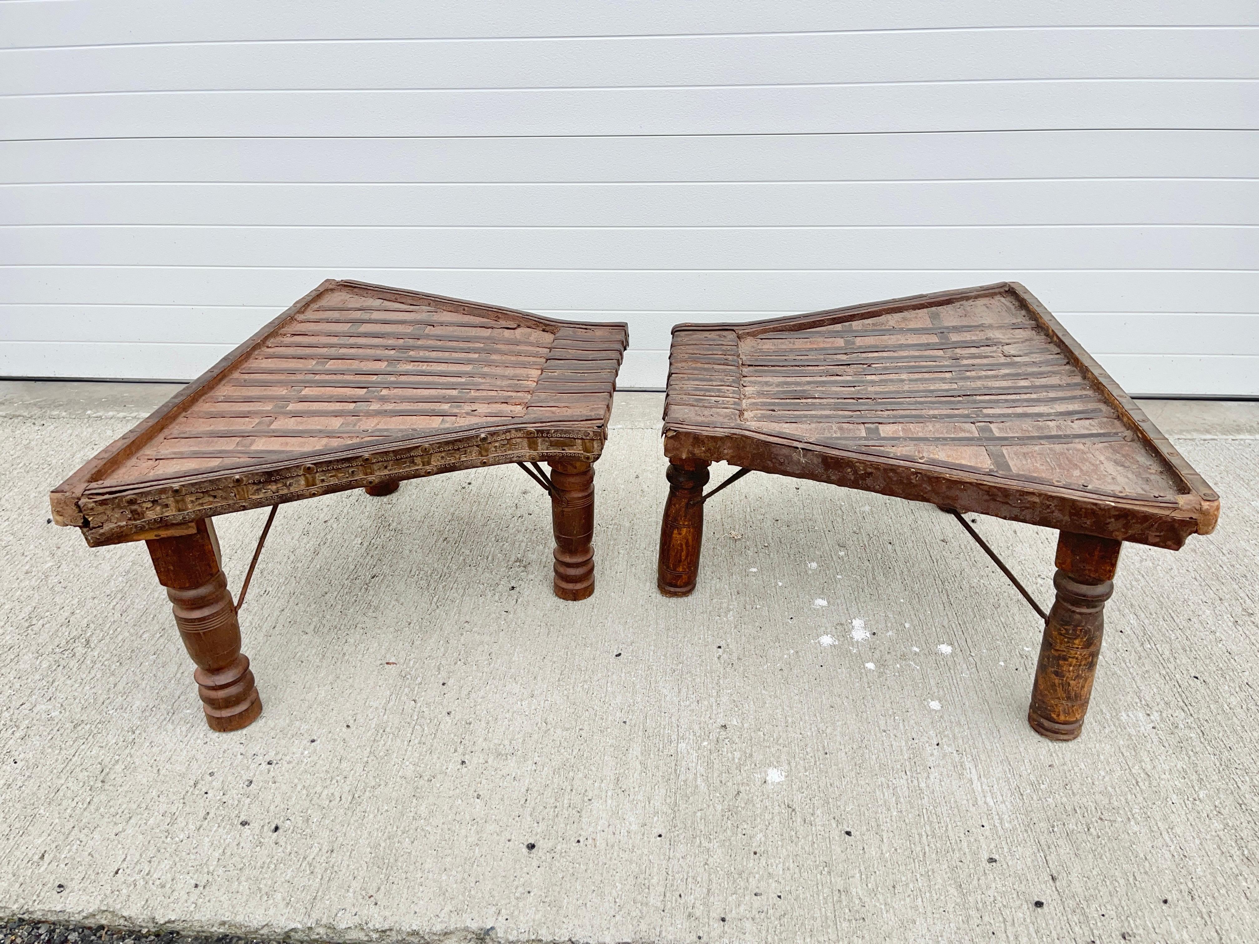 Paire légèrement asymétrique de tables à trois pieds de forme trapézoïdale du XIXe siècle, fabriquées à partir de l'avant de charrettes à bœufs de l'Inde et cerclées de bandes de fer et de cuivre forgées à la main. Elles peuvent être utilisées