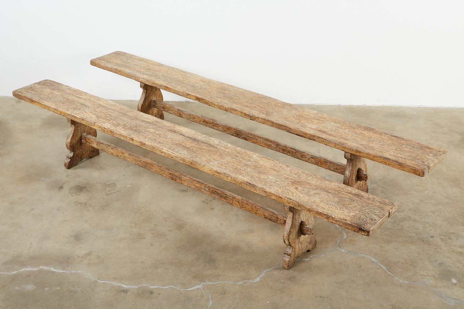 Fantastic pair of Italian Baroque style oak bench dining seats featuring an intentionally distressed lacquer finish and patina. Bespoke set of benches having a trestle style base with mortise and Tenon old world joinery. The long 1.5 inch thick