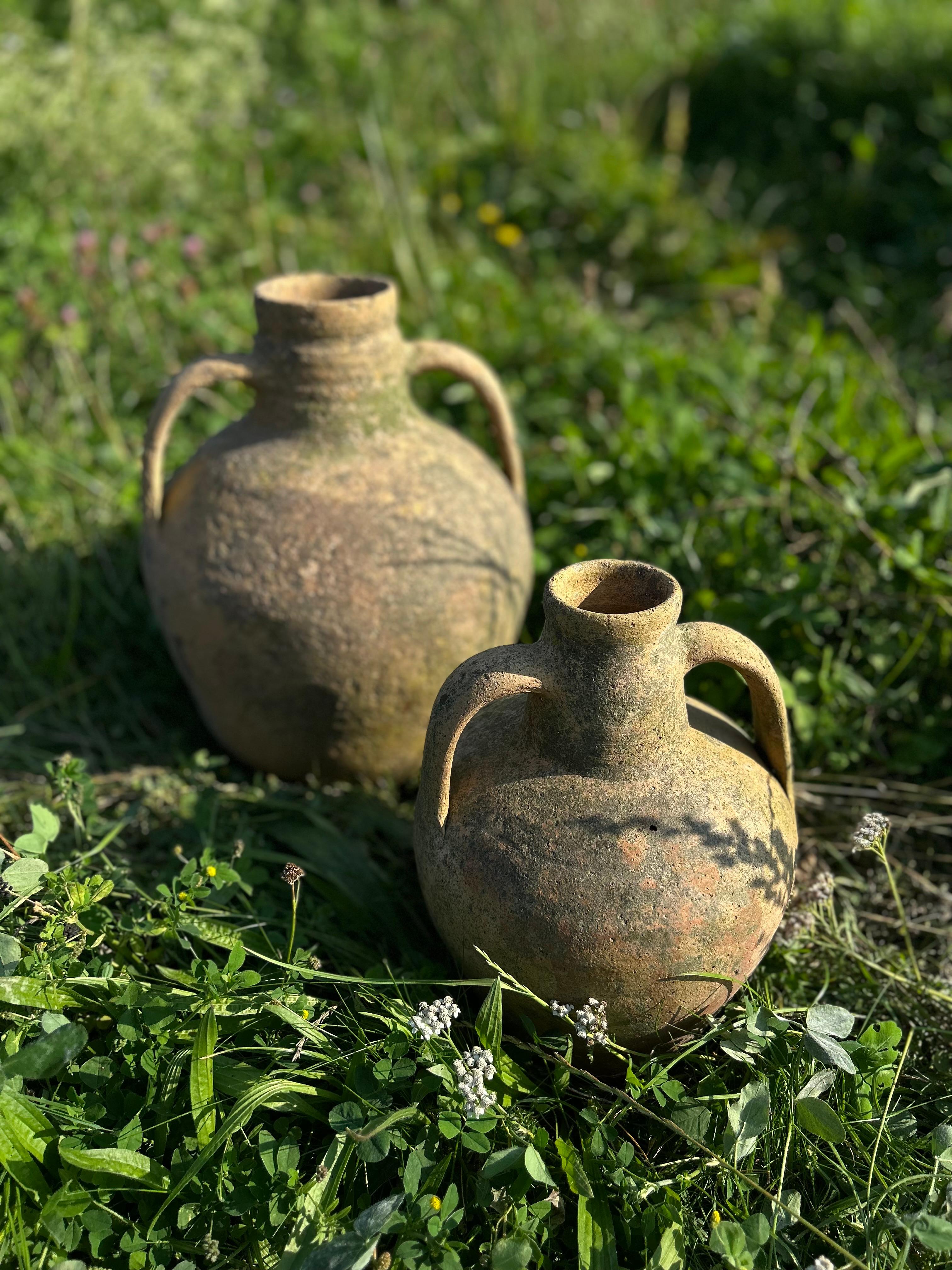 Le charme intemporel de la Méditerranée se retrouve dans cette paire de jarres à olives rustiques en terre cuite, datant du début du XXe siècle. Fabriquées avec un art méticuleux, ces jarres exhalent la chaleur des oliveraies et de la campagne