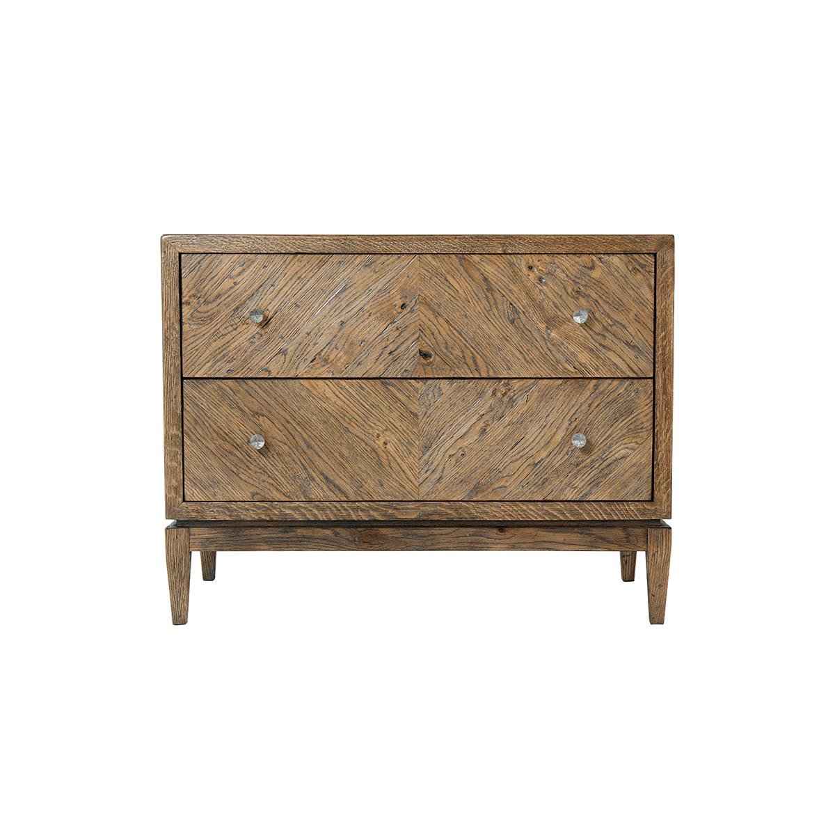 Rustic Oak two drawer nightstand with a light oak rustic finish, herringbone diamond parquetry design, two long drawers with vintage textured metal handles and raised on square tapered legs.

Dimensions: 35