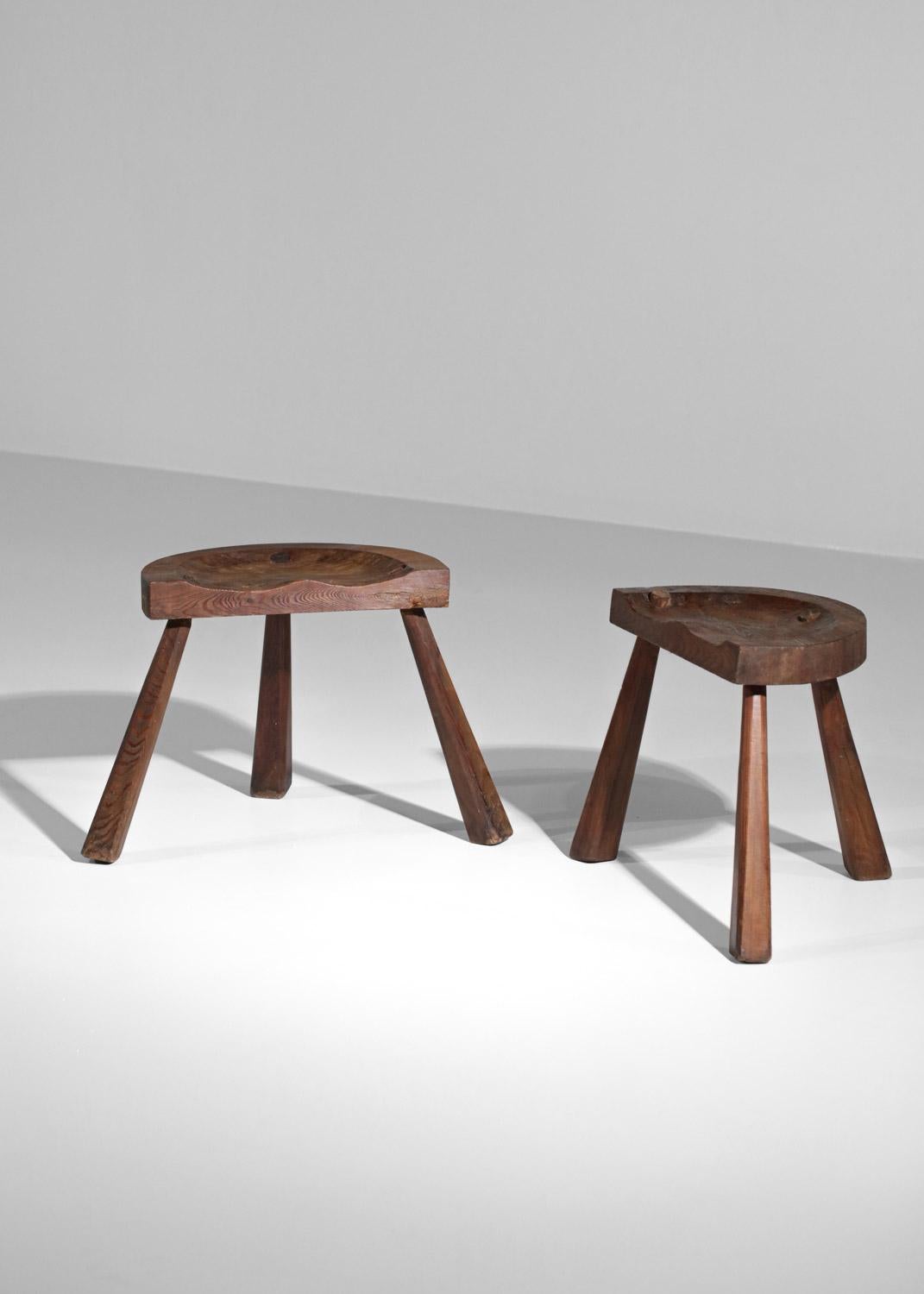 Set of two rustic vintage stools with a brutalist design in the taste of Jean Touret's work. Handcrafted work done with a gouge to carve the solid oak structure and the tripod legs. Beautiful patina of time on the wood (see photos).