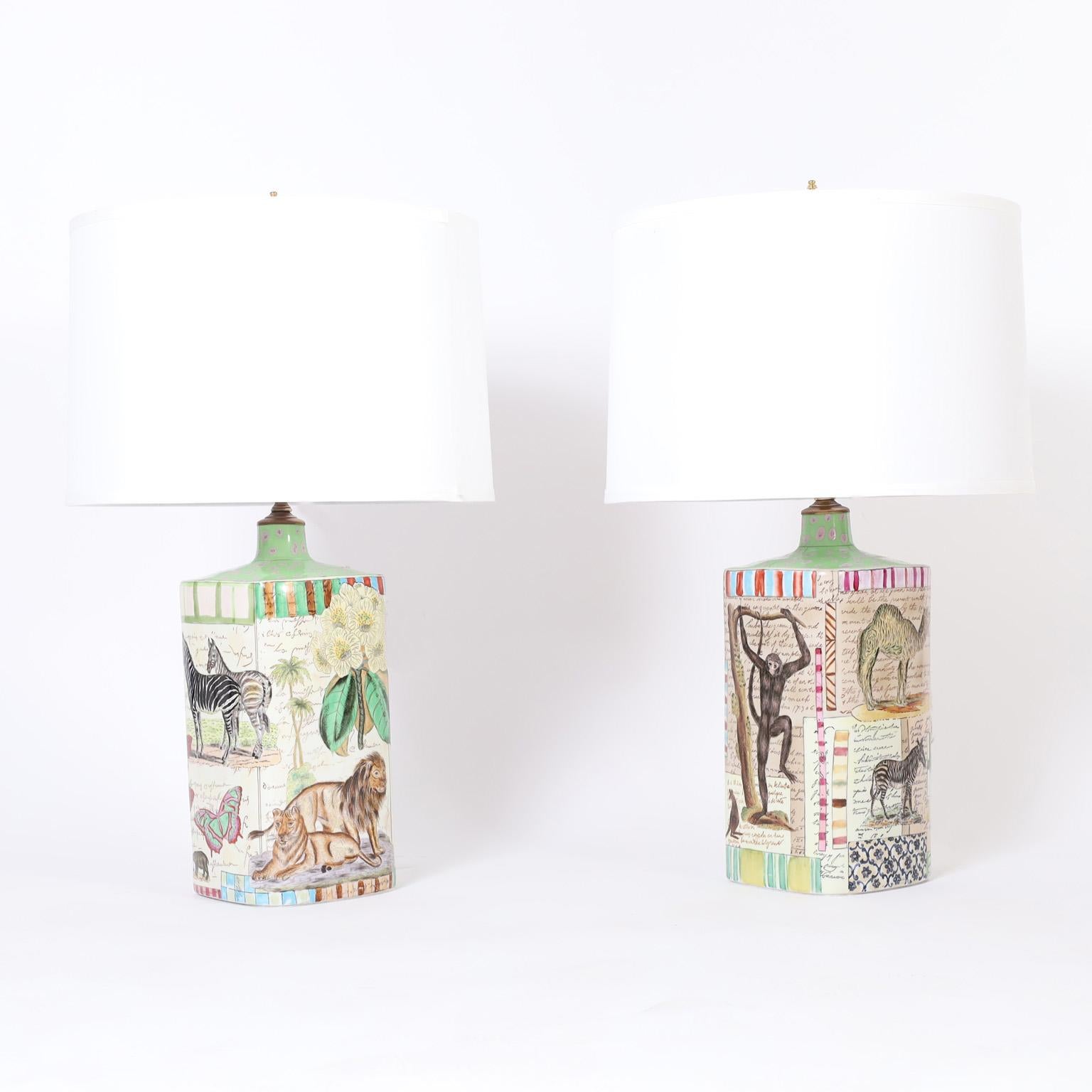 Transporting pair of ceramic table lamps decorated all around with animals on a faux scholastic background. Marked John Derian for Tozai on the bottom.