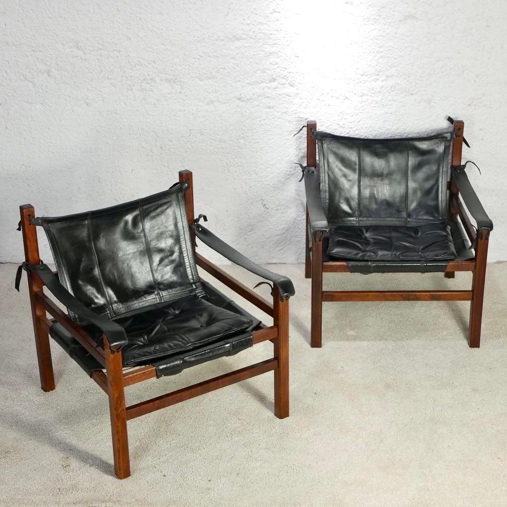 Beautiful pair of Safari armchairs, in the style of Arne Norell’s Sirocco chairs.
Wood structure, seats, backs and cushions in black leather, linked by leather straps. 
Cord bottom seats.
Really elegant and confortable.
Overall good condition, nice