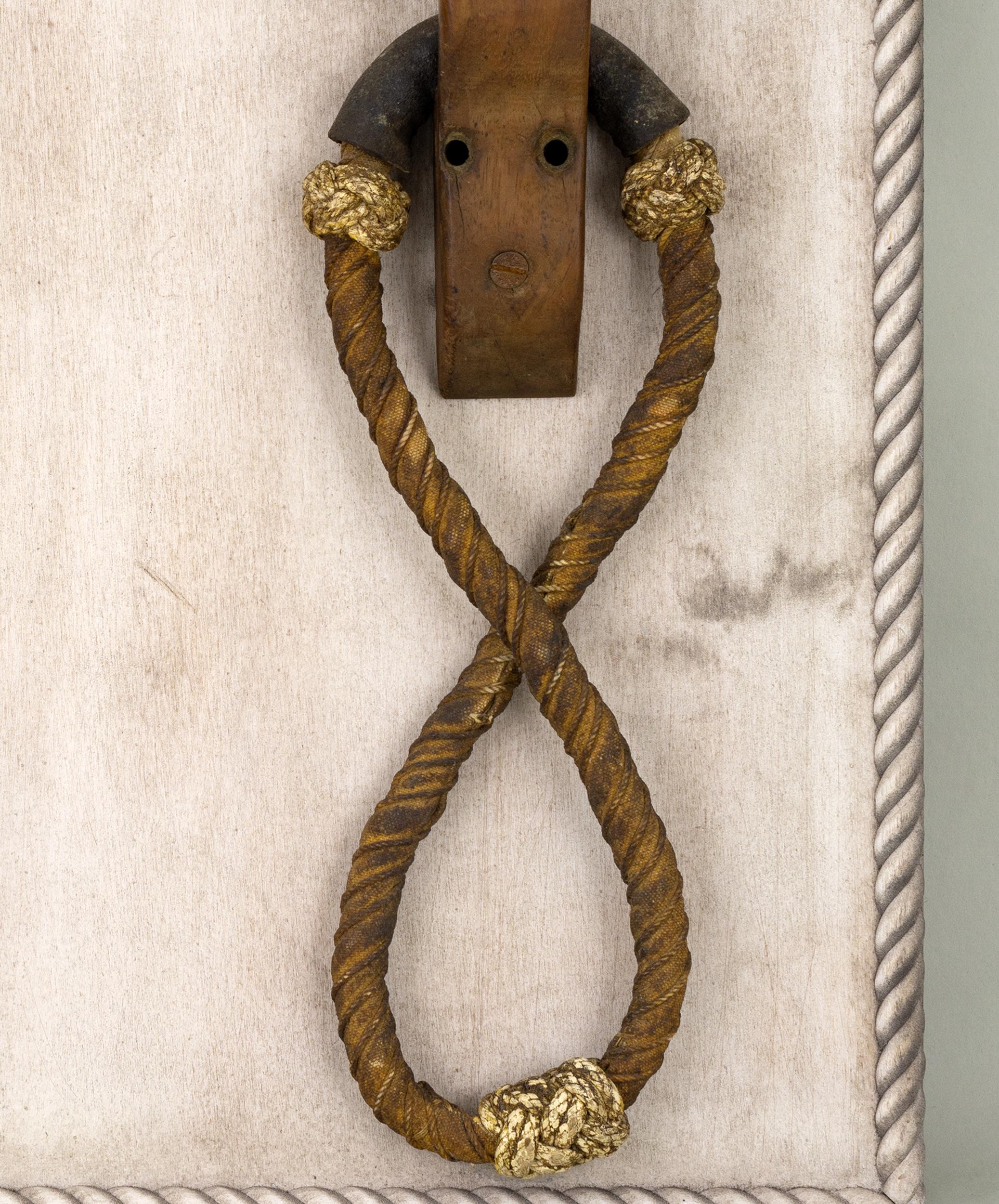 Rare sailor-made figure-eight rope beckets with natural canvas and cord covering, leather hinge roll, 'Turk's Head' macrame bumpers painted white, having carved mahogany brackets with five-pointed inlaid stars, mounted on a whitewashed board with