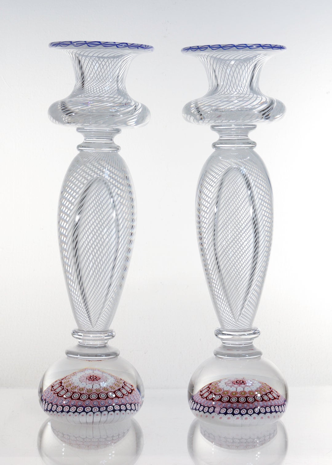 A rare pair of French paperweight candlesticks.

By the St. Louis Glass Company.

With latticino candle cups and bodies supported by paperweight bases with rows of concentric millefiori canes.

Each candle cups is finished with a blue and white