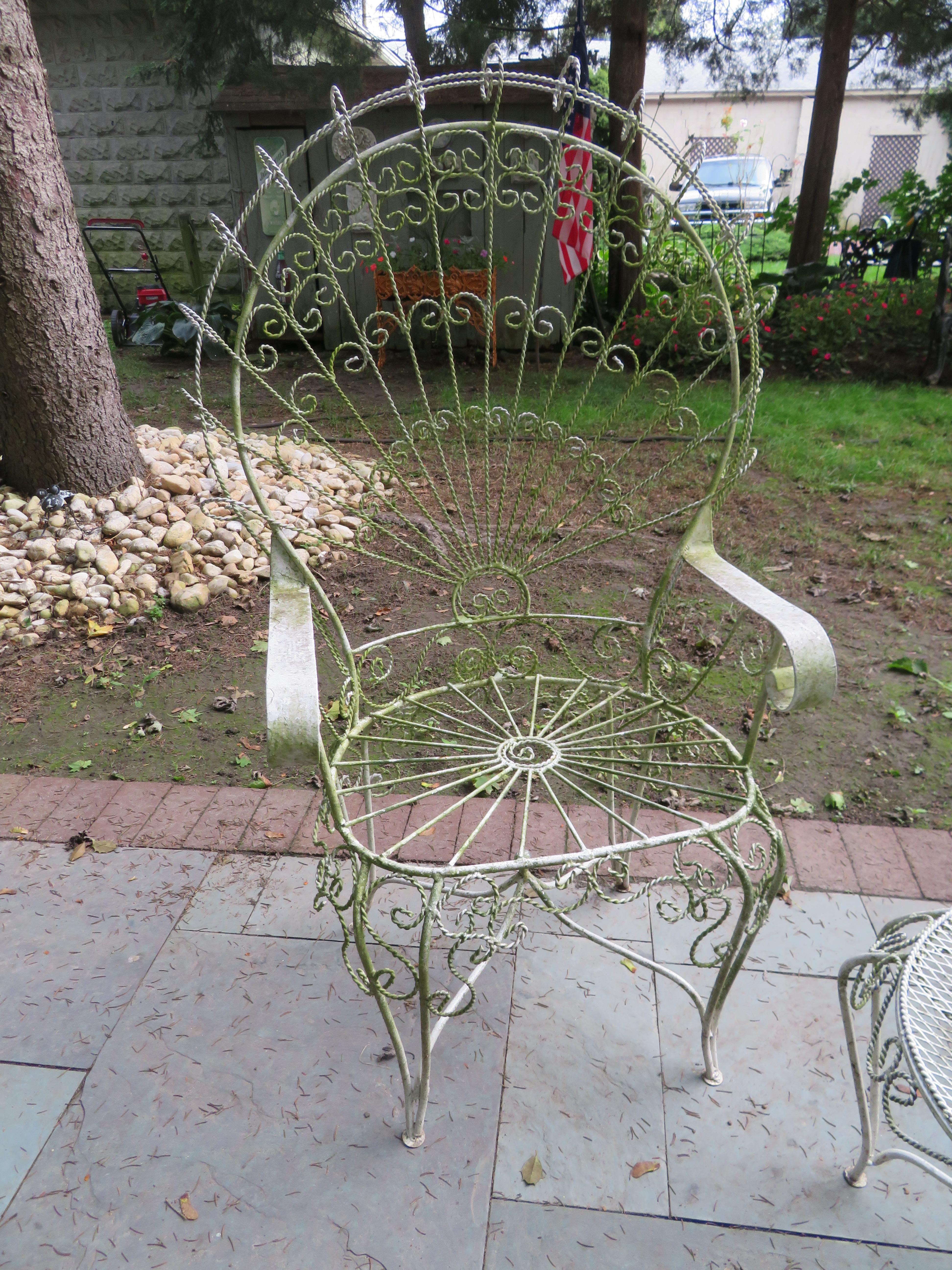 Gorgeous pair of Salterini ornate wrought iron twisted wire fan back patio chairs with matching side table. This pair is in vintage condition retaining their original white finish showing a wonderful greenish lichen patina. There are no cracks or