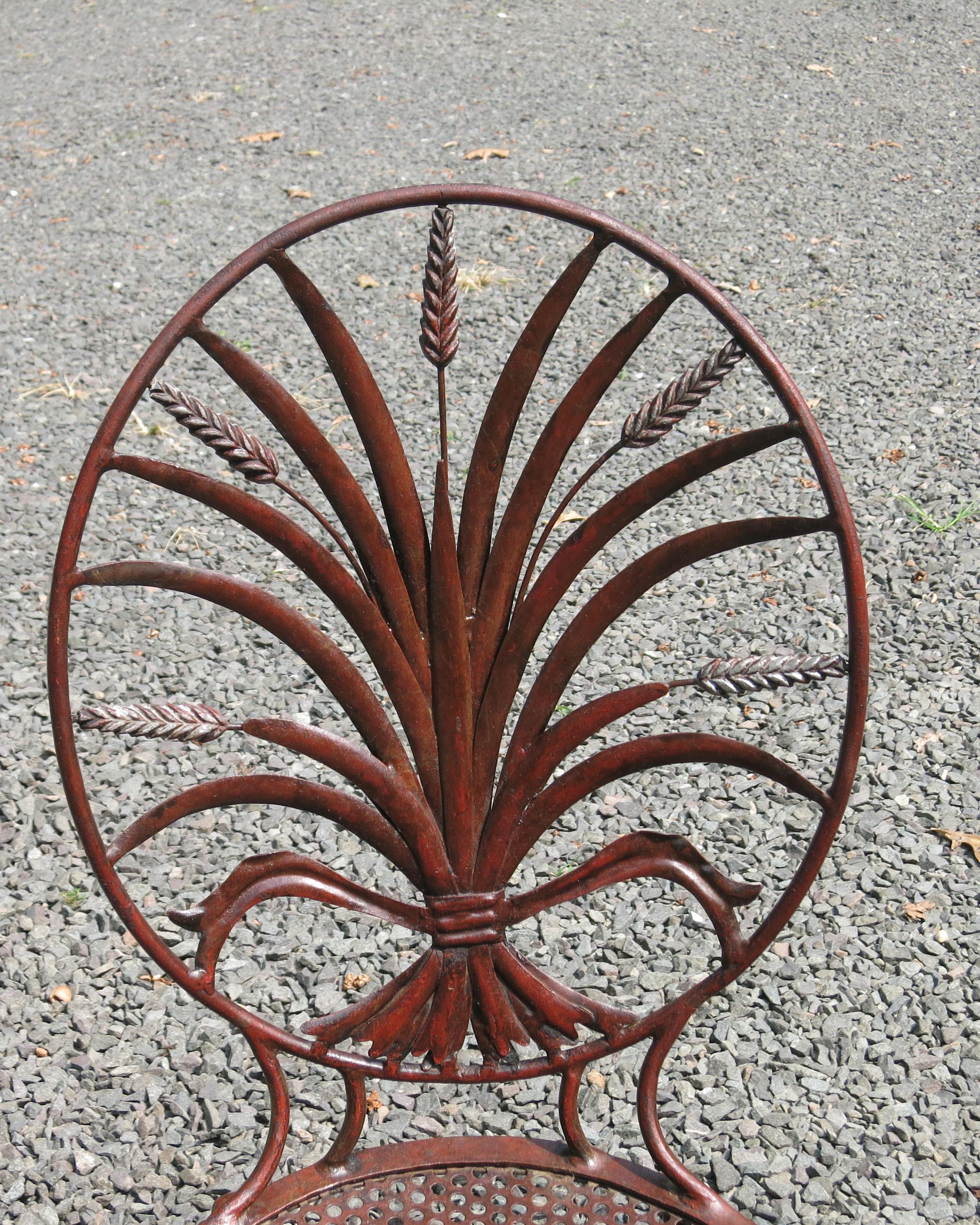 Nice distressed pair of Salvadori wheat back iron chairs. Paint loss and rust accent the chairs with a trace of gold gilt remaining. The seat height is 17