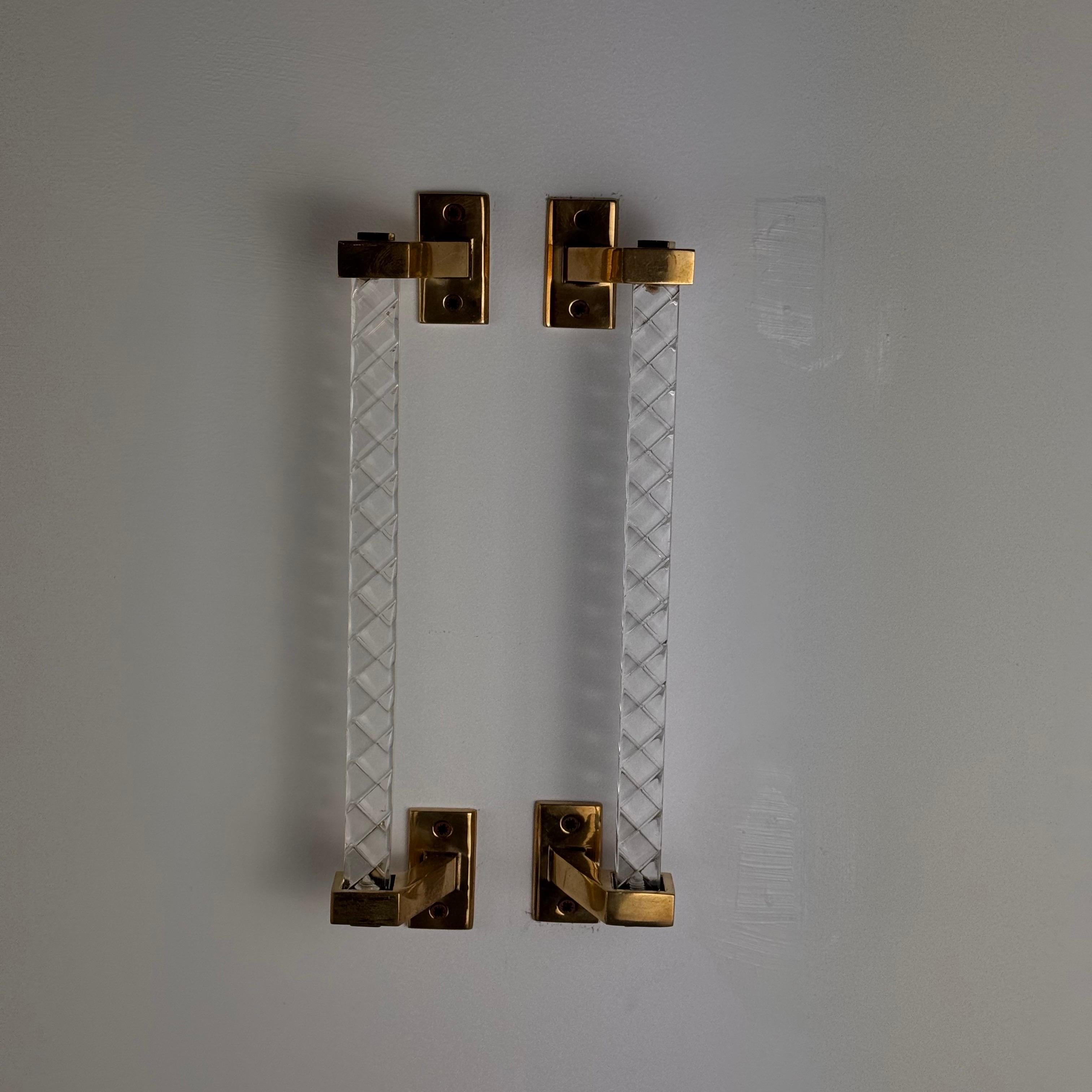 Questa squisita coppia di maniglie, disegnata da Sandro Petti e prodotta dalla rinomata Maison Jansen negli anni '60, emana raffinatezza ed eleganza senza tempo. Realizzate in ottone laccato oro e plexiglass lavorato, queste maniglie vantano