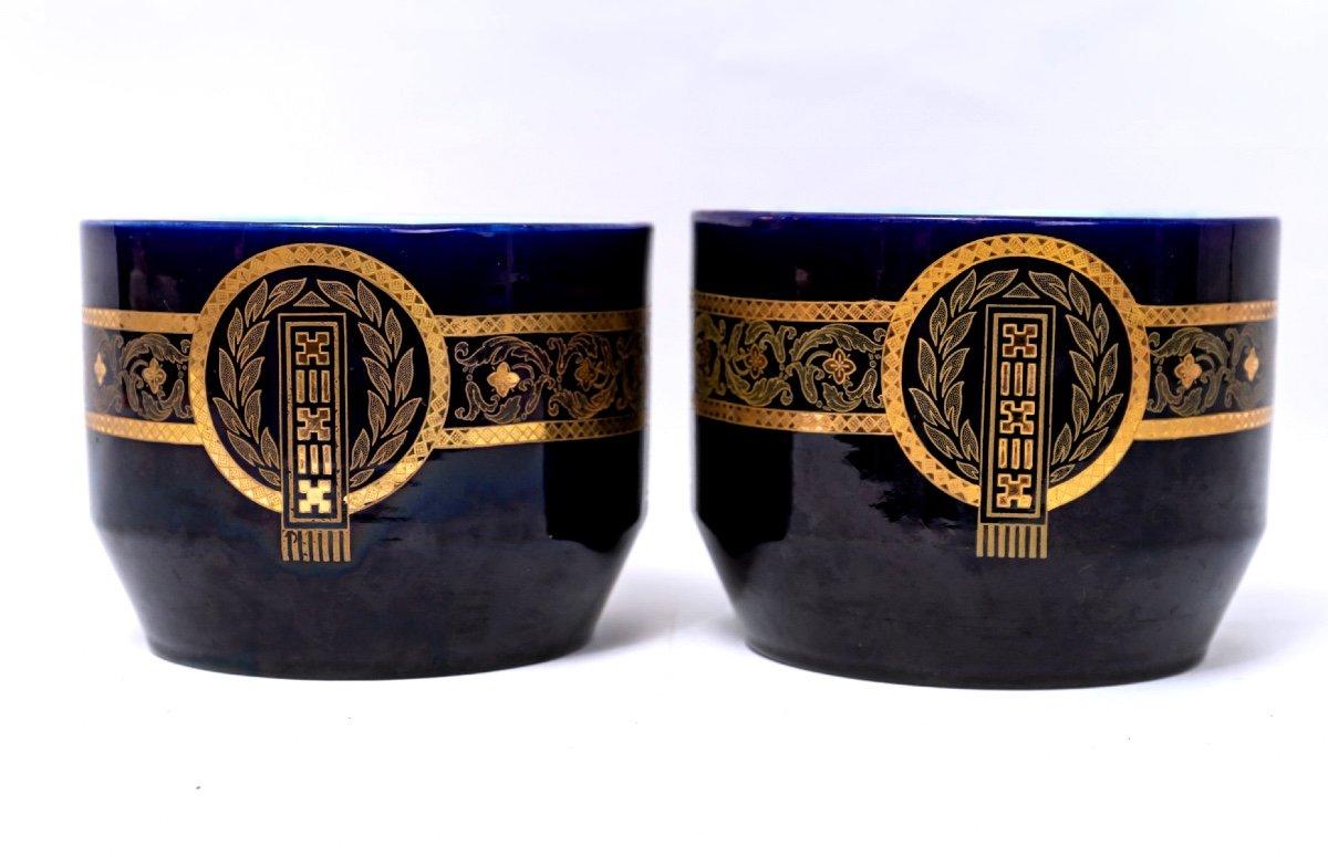 Rare et exceptionnelle paire de cache-pots en céramique de la très réputée faïencerie de Sarreguemines. 
Il s'agit d'une œuvre magnifique, très proche des bleus de Longwy, avec des motifs géométriques dorés sur un fond bleu marine profond et