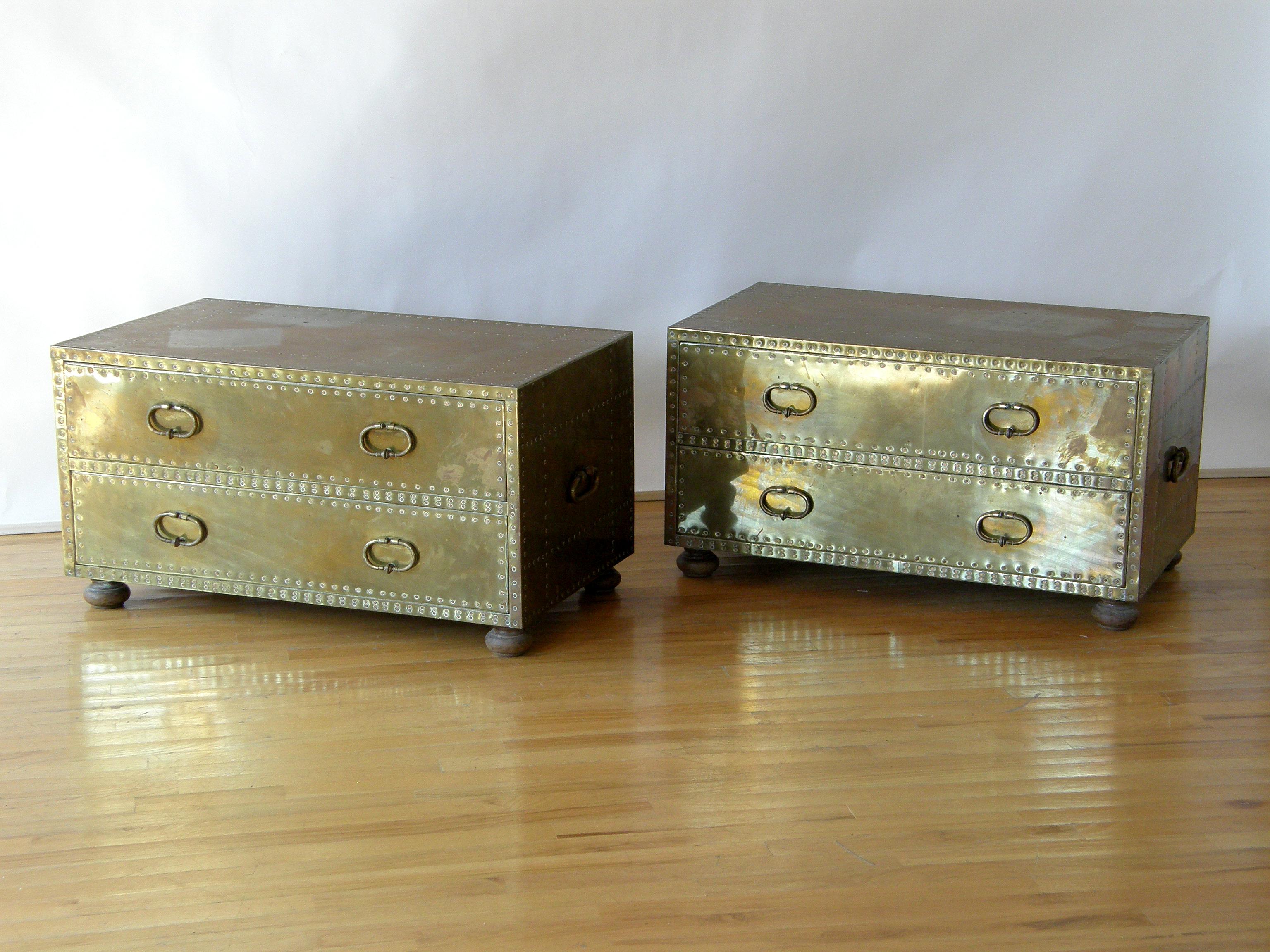 This pair of brass-clad, two drawer chests attributed to Sarreid are versatile storage pieces. The decorative nailhead patterns highlight the form. They look like a cross between a chest of drawers and a storage trunk. These can be used side by side