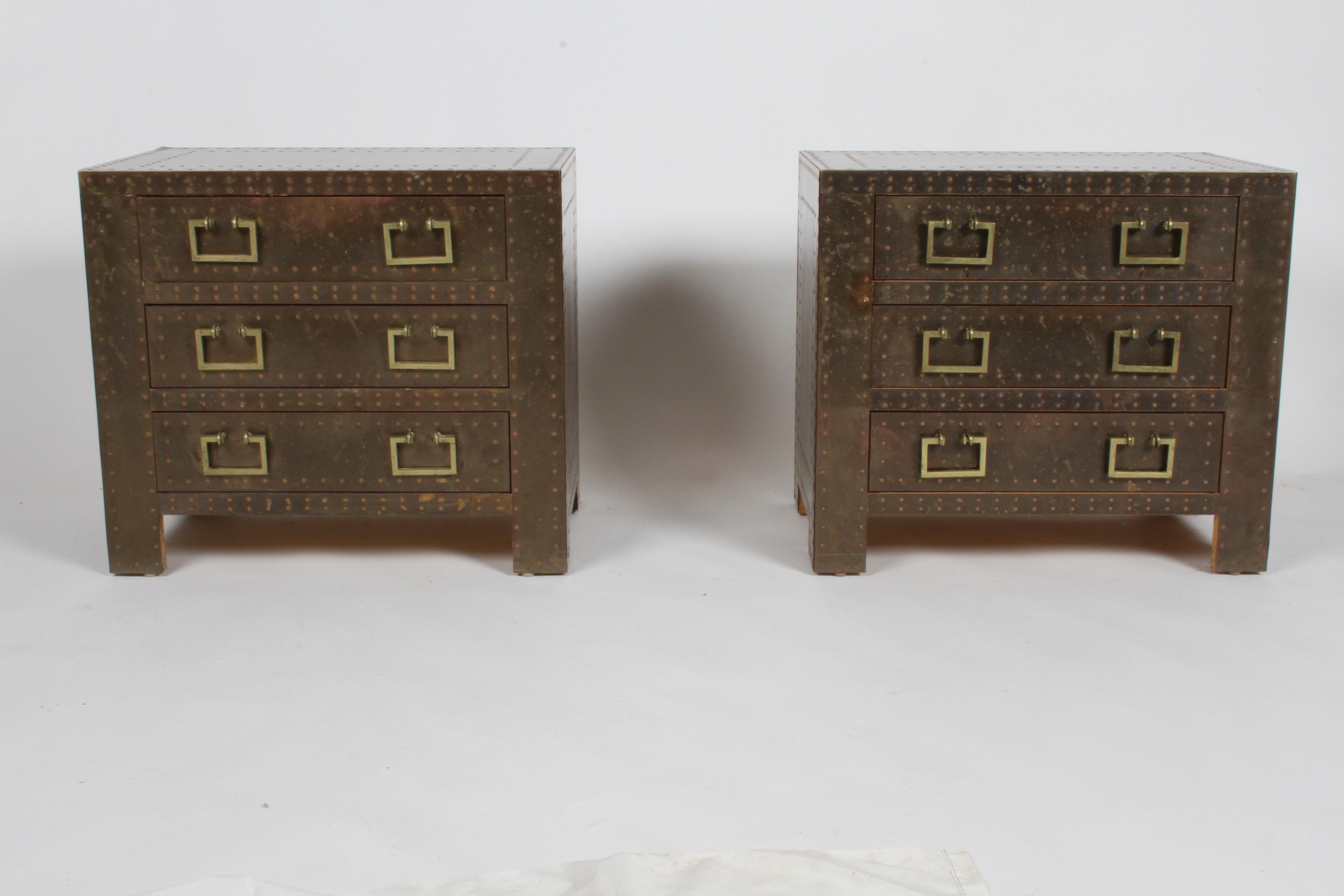 Vintage pair of Hollywood Regency Sarreid brass clad three drawer chests, with copper nail heads and brass handles. Great patina, all nails intact, no damage to brass edges. Chest are great for use for end tables or nightstands. Signed with brass