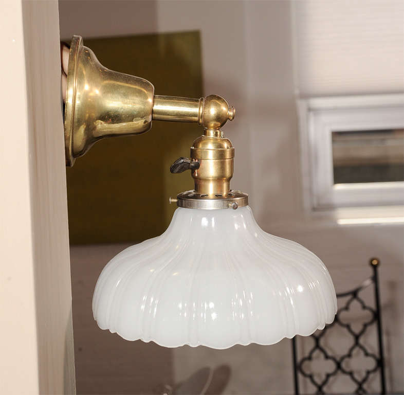 Pair of brass wall sconces or lamps with scalloped milk glass shades. USA, circa 1930.

Recently rewired with new sockets. Each sconce takes one standard base bulb (60 watts max).

Dimensions:
8.75 inch width overall (same as shade diameter)
8
