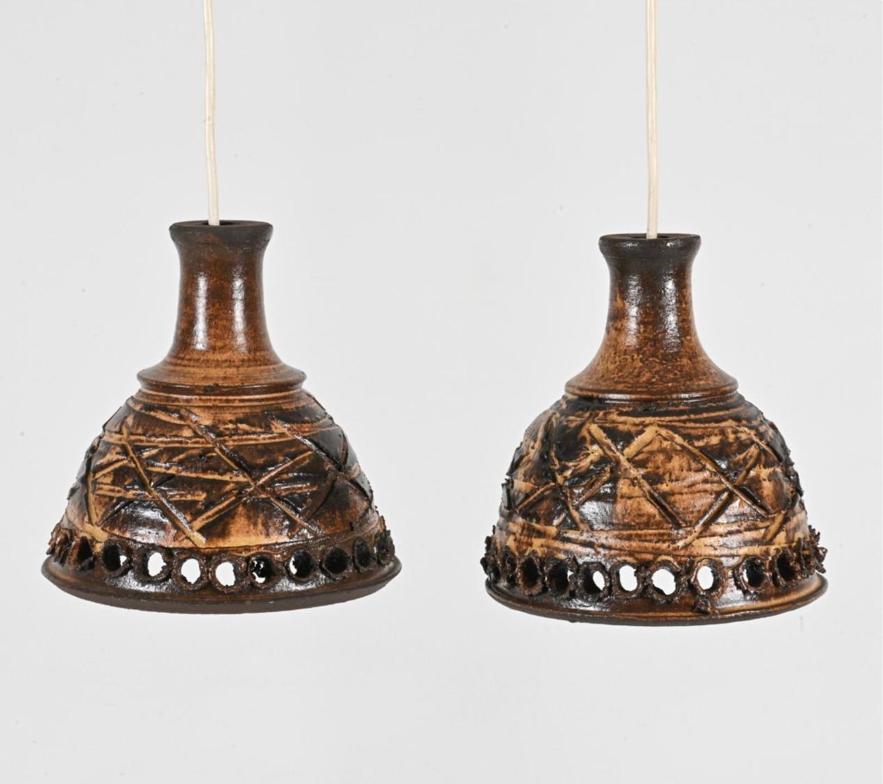 Paire de lampes suspendues scandinaves modernes en céramique émaillée faites à la main, danoises, vers 1960. La glaçure brune à trous comporte une douille d'ampoule et un fil électrique suspendu. Nécessité d'un câblage. 

Dimensions : H 8.25