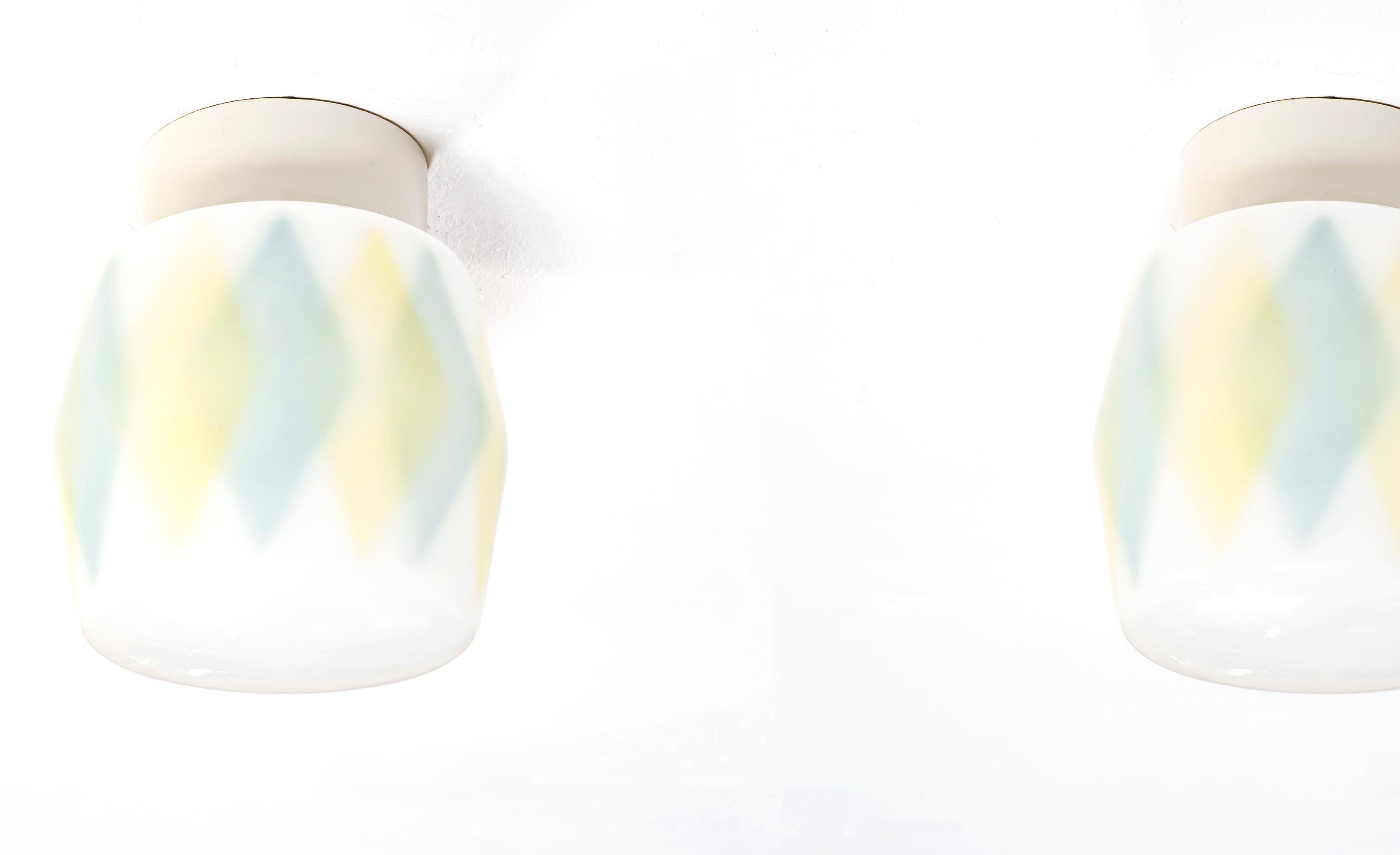 Wonderful pair of ceiling lights on a porcelain base with shades in decorated glass. Most likely designed and made in Norway from circa 1950s first half. Both lamps are fully working and in good vintage condition.