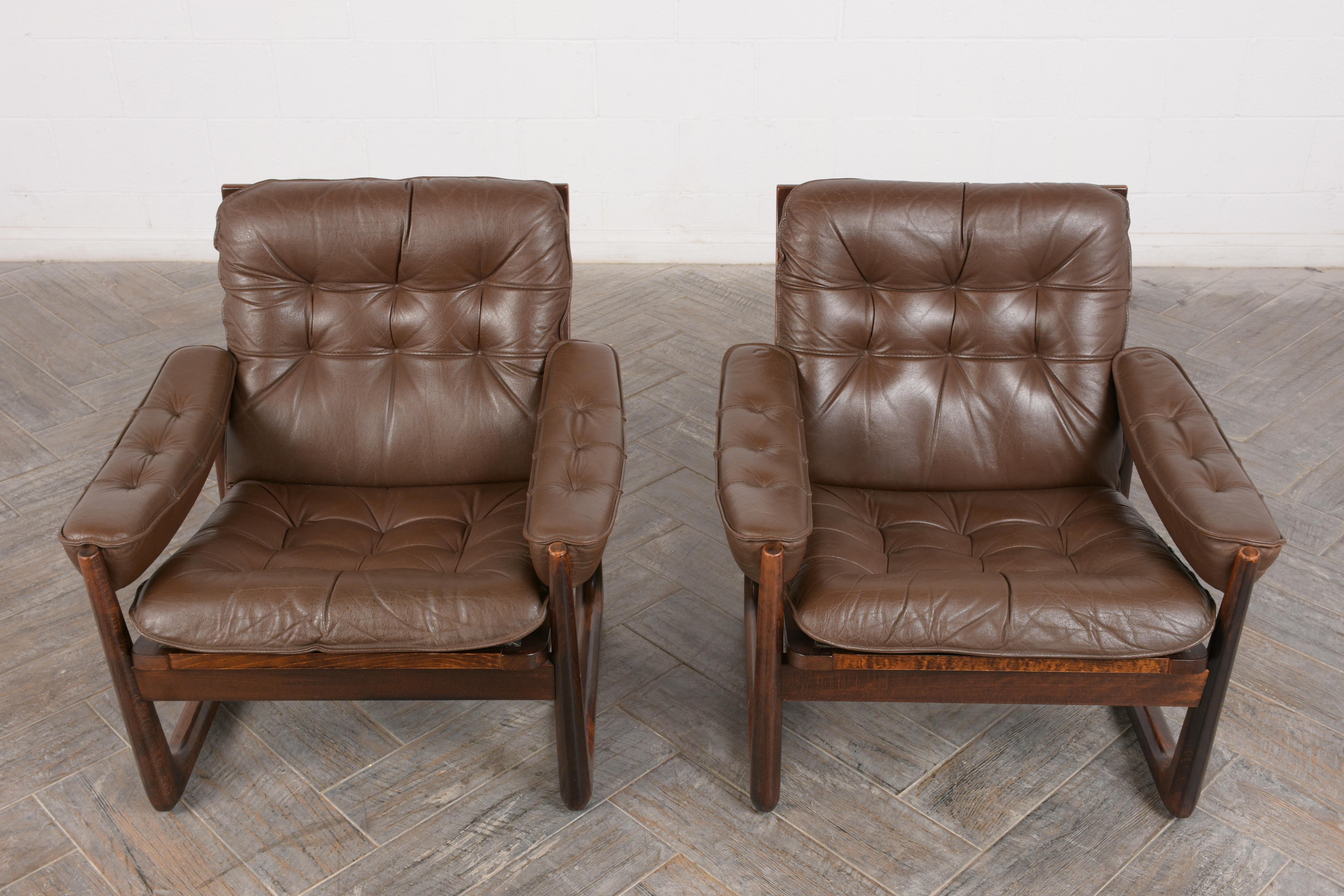 This pair of 1960's Danish Leather Lounge Chairs by Oddvar Vad is made out of solid rosewood with a patina finish and is professionally restored. These Bauhaus-style club chairs are upholstered in their original dark brown leather which is in great