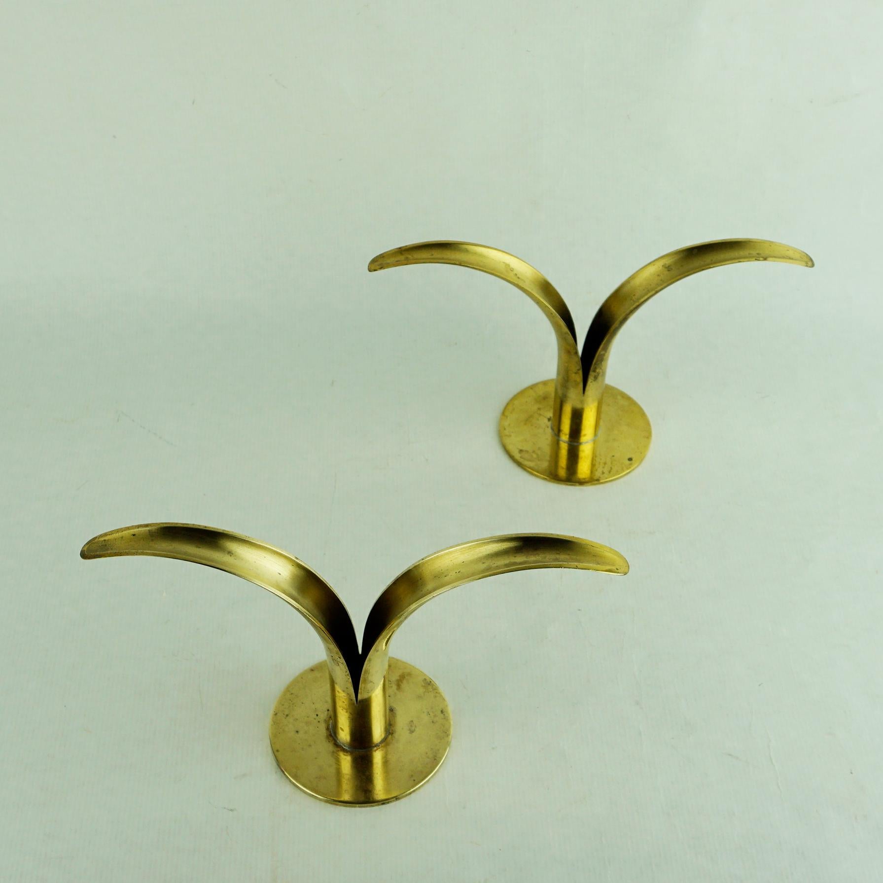 A pair of charming Lily (Liljan) candleholders, originally designed in 1939 by Ivar A°lenius Bjo¨rk (1905-1978) and produced in Sweden by Ystad-Metall, each in warm, polished brass. Each includes [IAB/Ystad-Metall/Made in Sweden] stamped to the