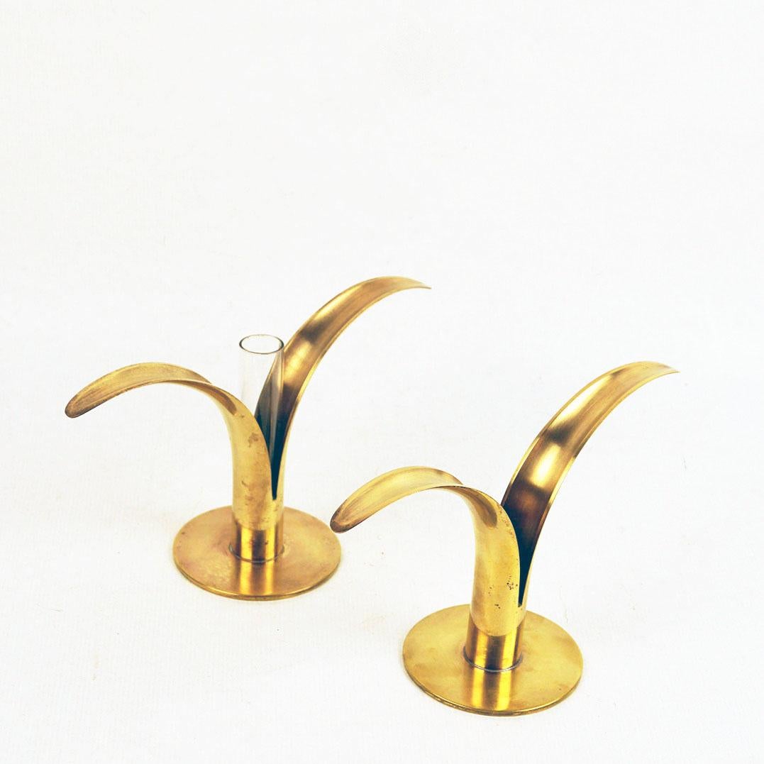 A pair of charming Lily (Liljan) candleholders, originally designed in 1939 by Ivar Alenius Björk (1905-1978) and produced in Sweden by Ystad-Metall, each in warm, polished brass. One of them with glass so it can also be used as vase or the glass