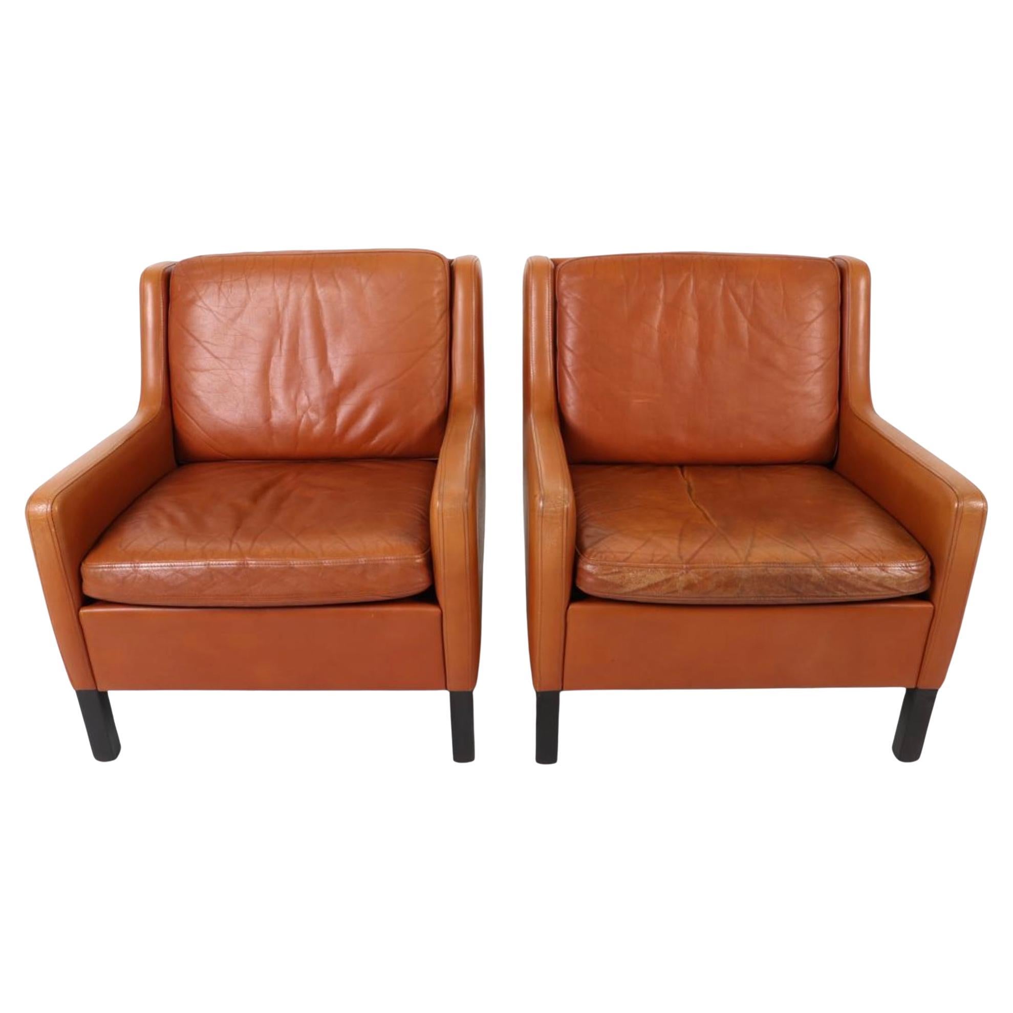 Schönes Paar Mid Century Scandinavian modern Cognac Leder Lounge-Stühle mit schwarzem Lack Beine. Leder zeigen schöne Patina mit Anzeichen von Gebrauch und Alter. Sehr bequeme Stühle, ideal für Ihr Strandhaus oder Haus in den Bergen. Sehr hohe