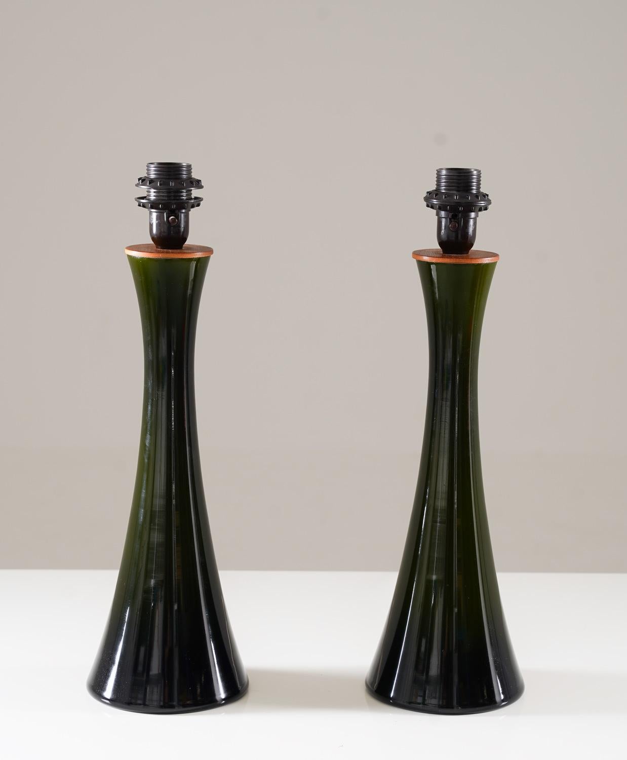 Paar Tischlampen, hergestellt von Bergboms, Schweden, 1960er Jahre.
Die Lampen bestehen aus dunkelgrünem sanduhrförmigem Glas mit einer Teakholzplatte, die das Leuchtmittel aufnimmt.
Die (neuen) Lampenschirme können auf Wunsch mitgeliefert