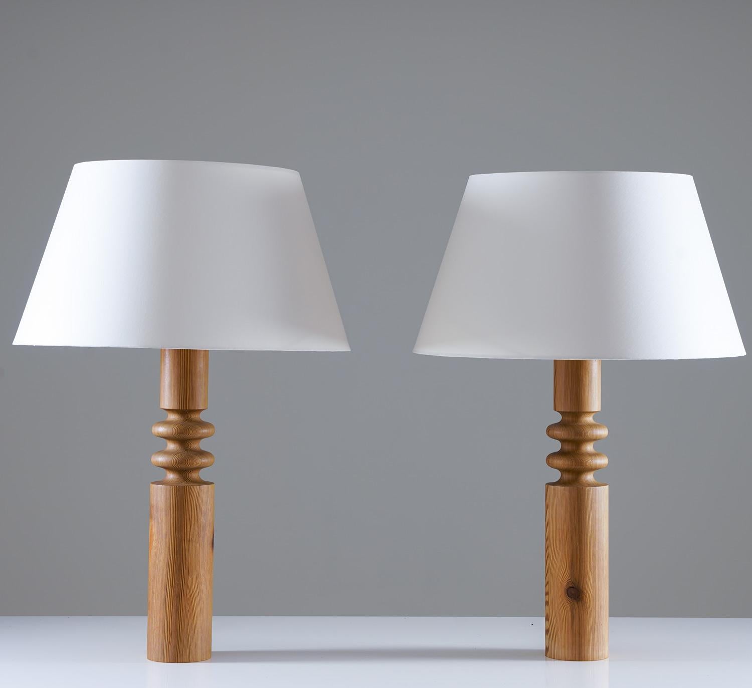 Set of two large table lamps by Östen Kristiansson for Luxus, Sweden, 1970s.
The lamps consist of a base of turned pine, that have aged beautifully. 
The lamps come with new high-quality shades in off-white satin fabric.

Condition: Very good