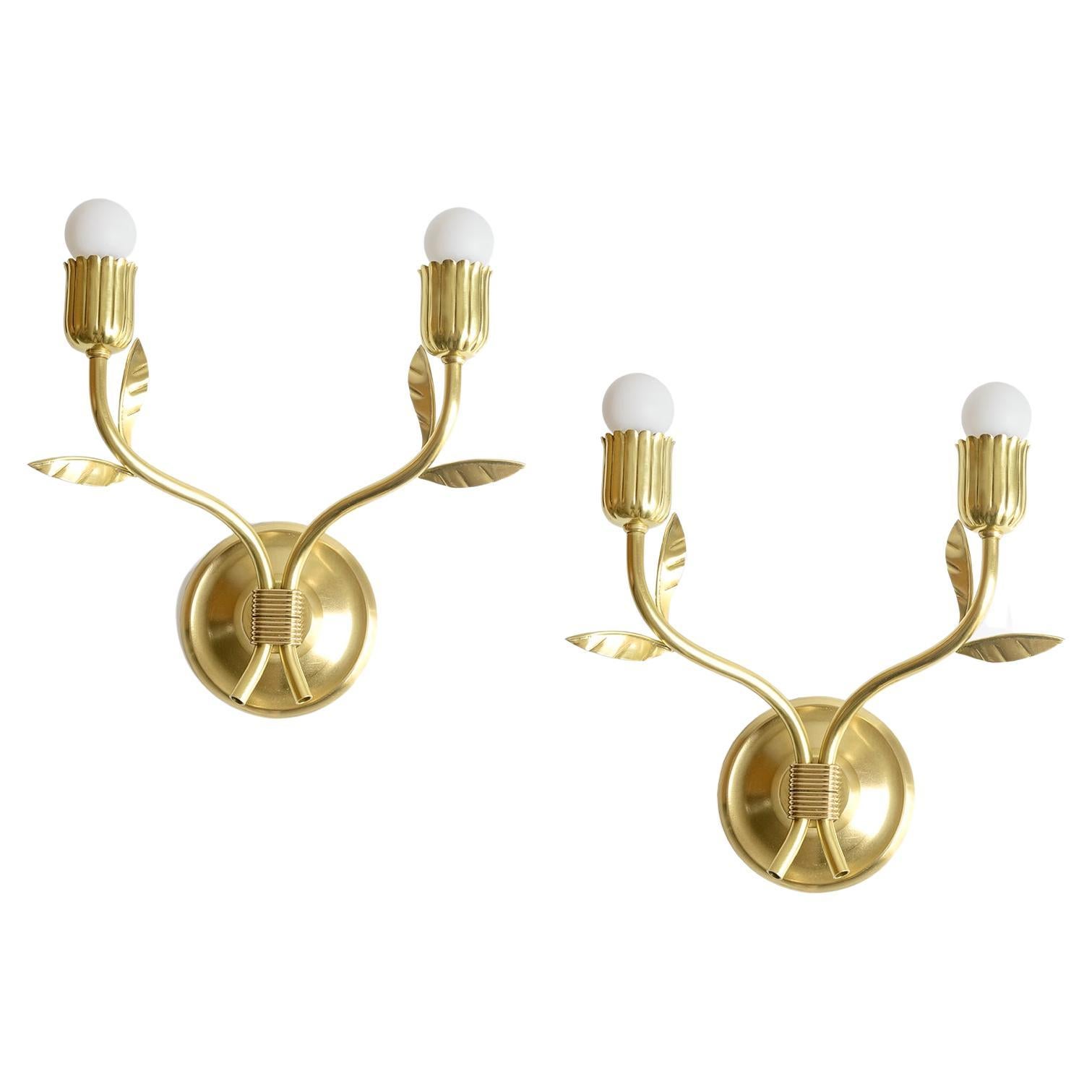 Pair of polished double arm, Scandinavian Modern wall sconces in polished brass. Each sconce has a pair of branch like arms with leaves and a floral bud socket holder. The backplate is cast brass and will fit any a standard electrical wall box. The