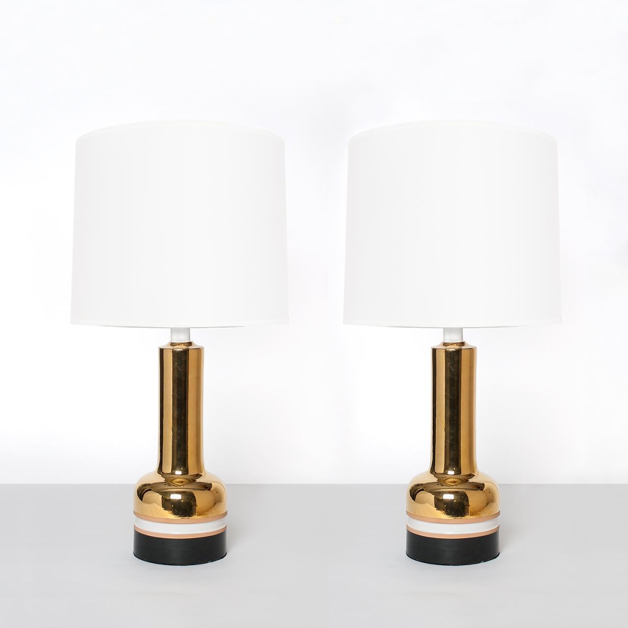 Pair of Scandinavian Modern ceramic table lamps with brilliant gold glaze made in Italy for Bergboms of Sweden. The lamps are detailed with unglazed and glazed bands in black and white. Newly re-wired for the USA with polished brass double socket