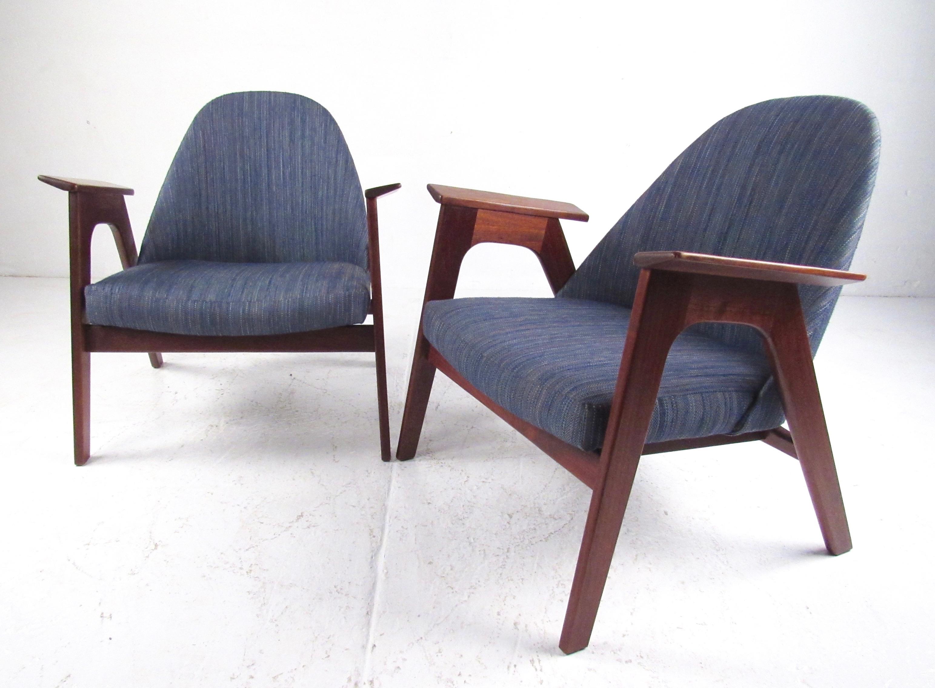 This striking pair of Mid-Century Modern lounge chairs feature comfortable sculpted seat backs, sturdy hardwood frames, and have been recently reupholstered. Designed in the style of Ib Kofod-Larsen. 
Please confirm item location (NY or NJ).