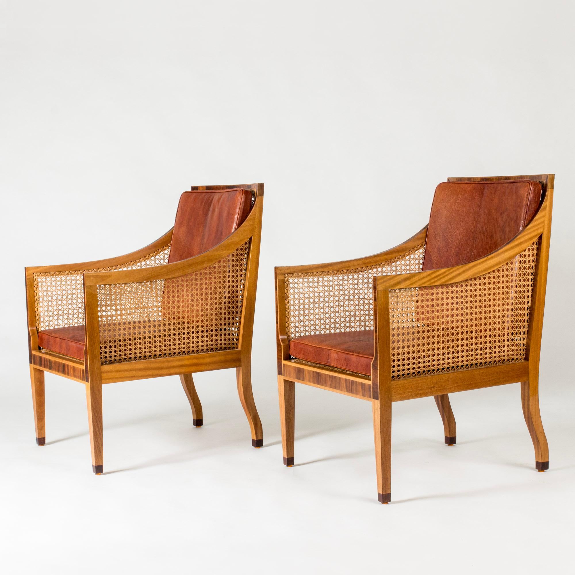 Pair of striking lounge chairs by Kaare Klint, “Model 4488”. Made from mahogany with elegant rosewood inlays and feet. Rattan seats, backs and sides, loose cushions with original cognac leather.