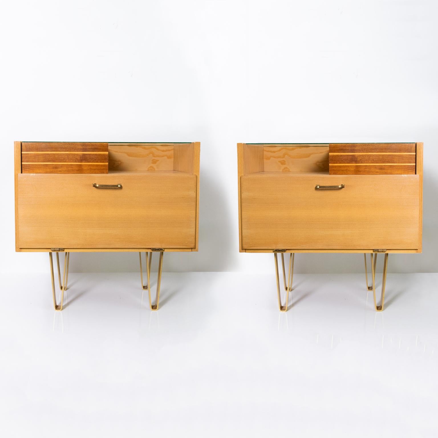 Pair of Scandinavian Modern nightstands in a pale elmwood detailed with solid teak. Each cabinet has a single pull out drawer and a drop door compartment. The legs are plated matte brass in “V” form. Very good original condition, maker unknown circa