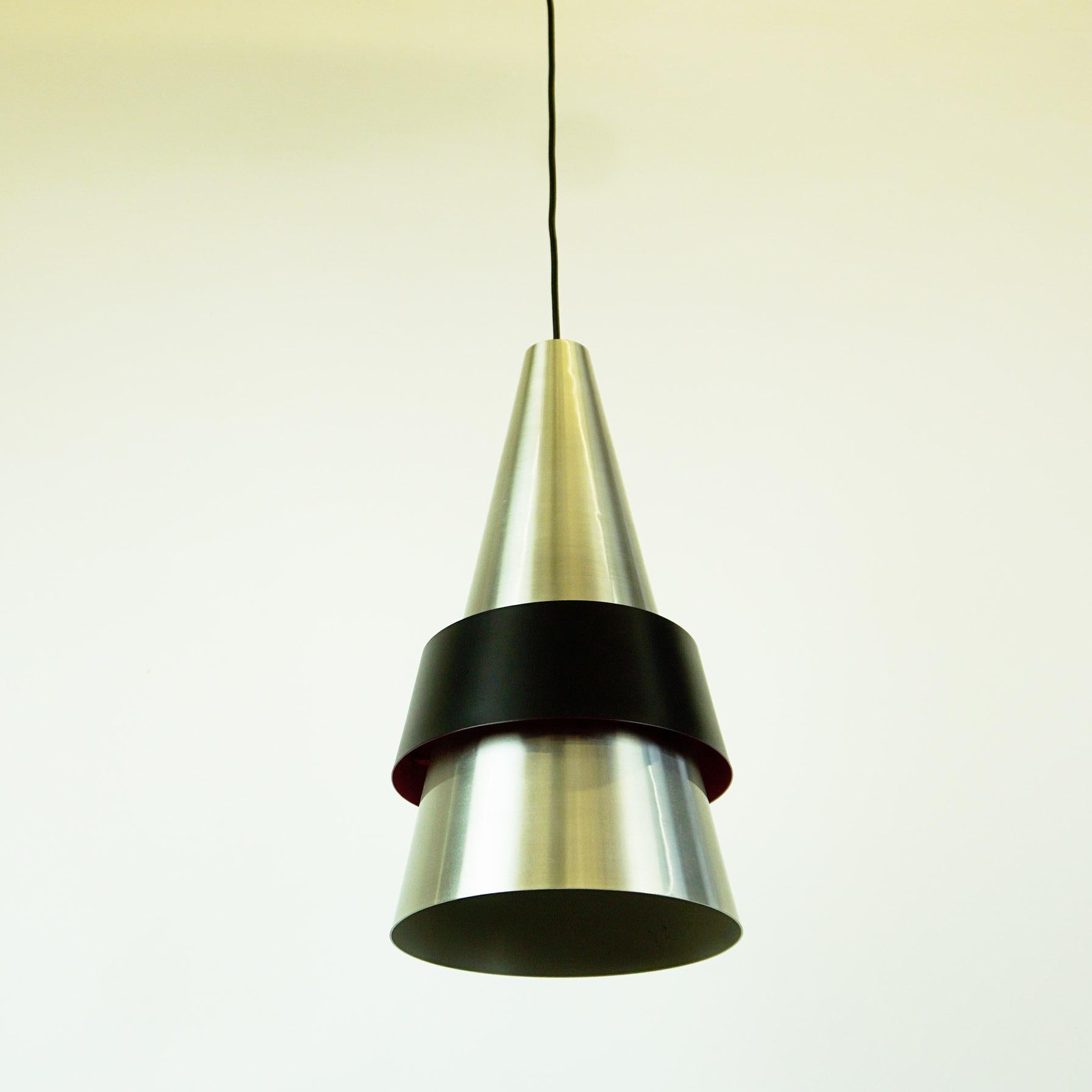 Large conical silver and black pendant lamps made from brushed aluminium set with a matte black shade. The Model is called Corona and was designed by Jo Hammerborg and manufactured by Fog and Morup in the early 1960s.
Both feature a pink colored