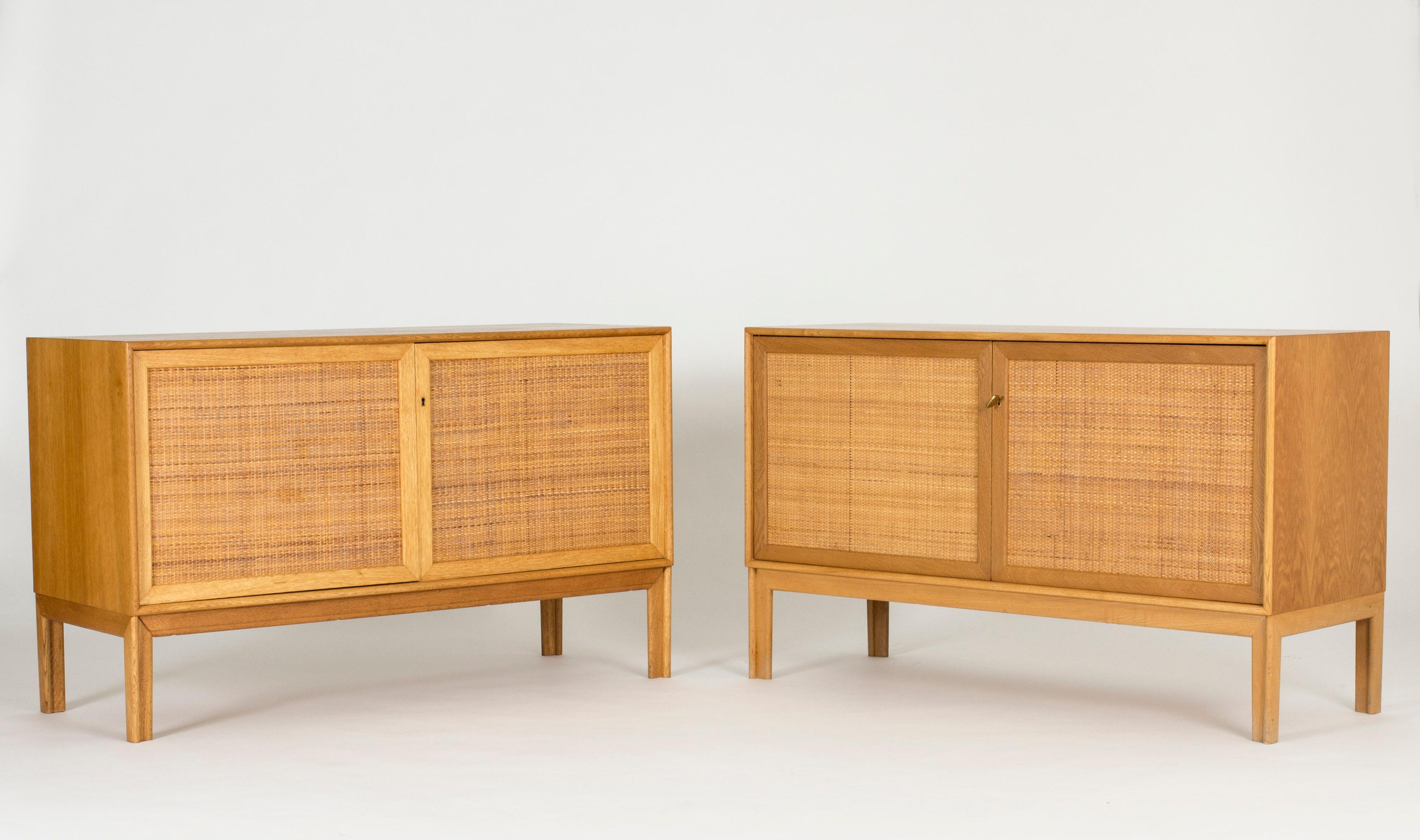 Pair of oak sideboards with beautiful rattan fronts, designed by Alf Svensson for Bjästa. Two shelves inside each sideboard separated by a wall in the center. Cool, large brass keys and nicely sculpted legs. Some variation in the color of the wood