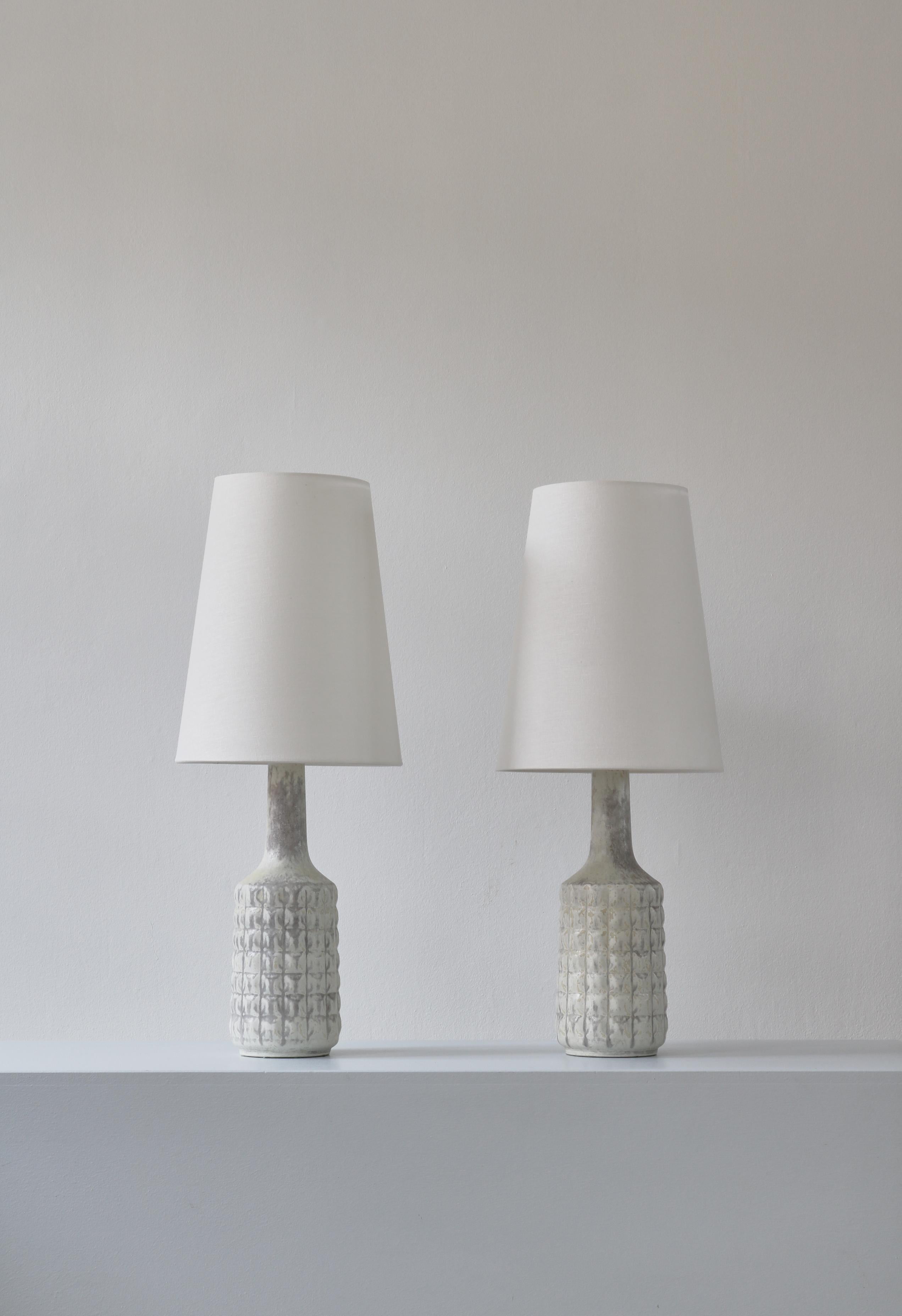 A wonderful pair of Scandinavian Modern unique table lamps made at Desiree stoneware workshop in Copenhagen in the 1960s. The lamp bases are handmade and decorated with an amazing white & grey glazing. Both lamps are signed. Equipped with white flax