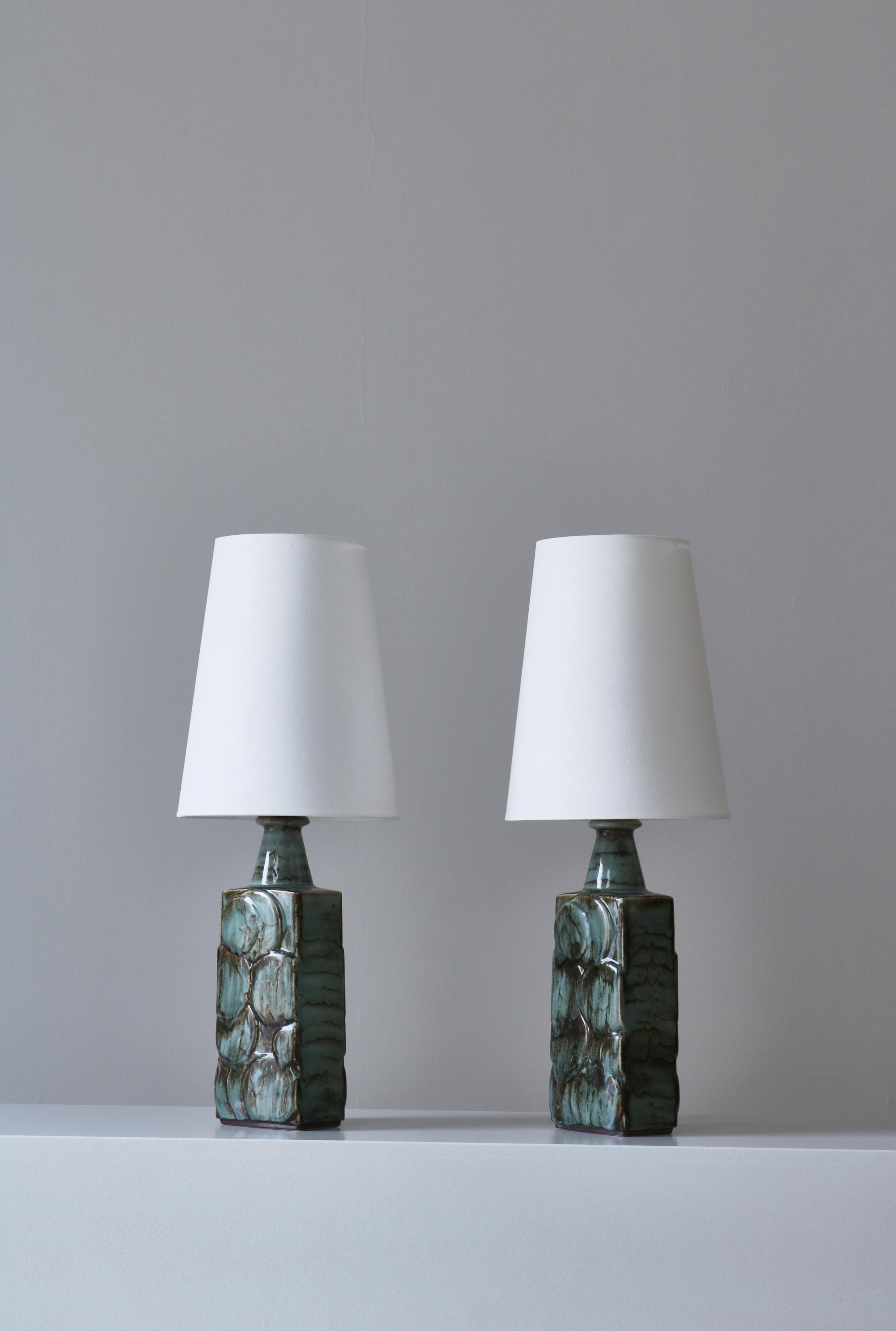 Ein wunderschönes Paar skandinavisch-moderner Tischlampen, die in den 1960er Jahren in der Steinzeugwerkstatt Désirée in Kopenhagen hergestellt wurden. Die Lampensockel sind handgefertigt in Reliefdekor mit einer ausdrucksstarken Glasur. Beide