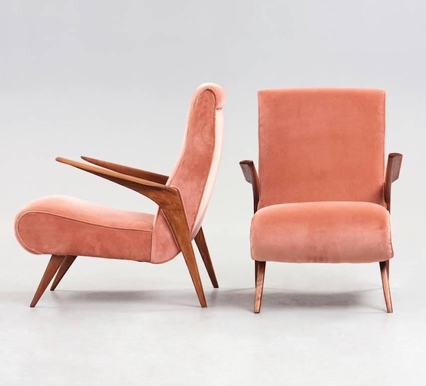 Pair of Scandinavian Modern style armchairs from the 1950s. Lightly floating wooden armrests. Seat and back upholstered with salmon pink velvet fabric. Slightly slanted legs of lacquered wood.