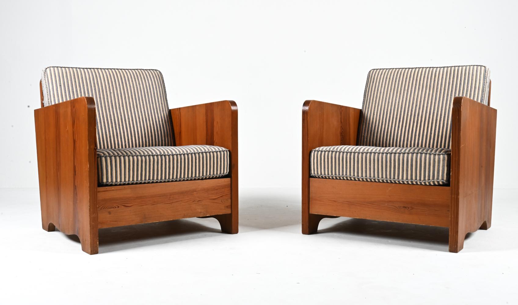 Ajoutez une dose tout à fait unique de charme rustique avec cette paire exceptionnelle de fauteuils Early Modern attribués à Axel Einar Hjorth. Luxuriez dans la riche texture naturelle des cadres en pin massif tandis que les épais coussins à