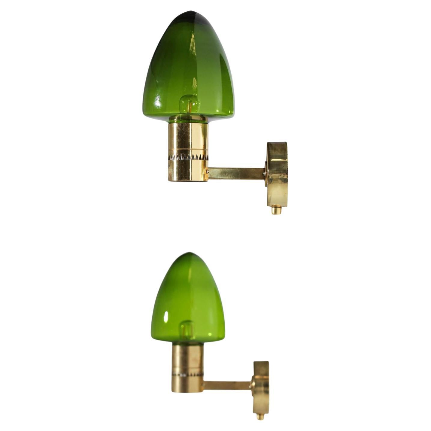 Pair of Scandinavian wall sconces by the famous Swedish designer Hans Agne Jakobsson. Model designed in the 50's. Structure of the sconces in brass and green transparent glass globe. Very nice vintage condition with traces of use and time (see