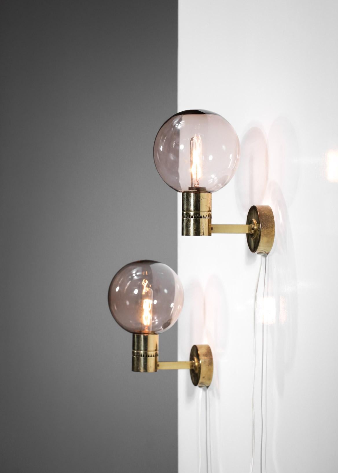 Pair of wall lights by the famous Swedish designer Hans Agne Jakobsson from the 60s. Structure in solid perforated brass and globes in smoked glass. Recommended bulbs type E14. Excellent vintage condition (see pictures).