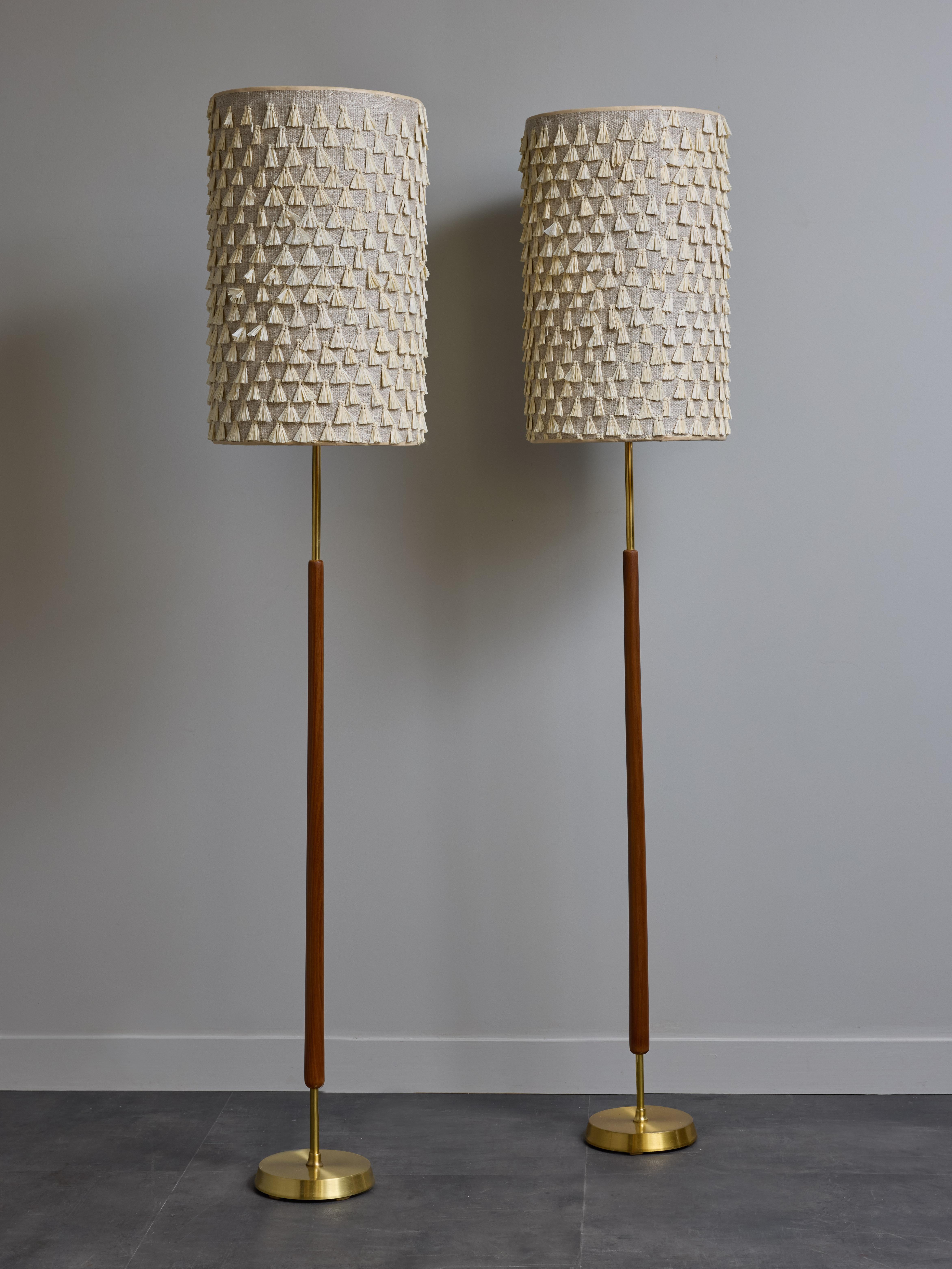 Coppia di eleganti lampade da terra scandinave di metà secolo composte da un corpo centrale in legno con piedi e colli in ottone, sormontato da un paralume moderno con tessuto Nobilis.

Dimensioni con i paralumi: ø30 H160cm
