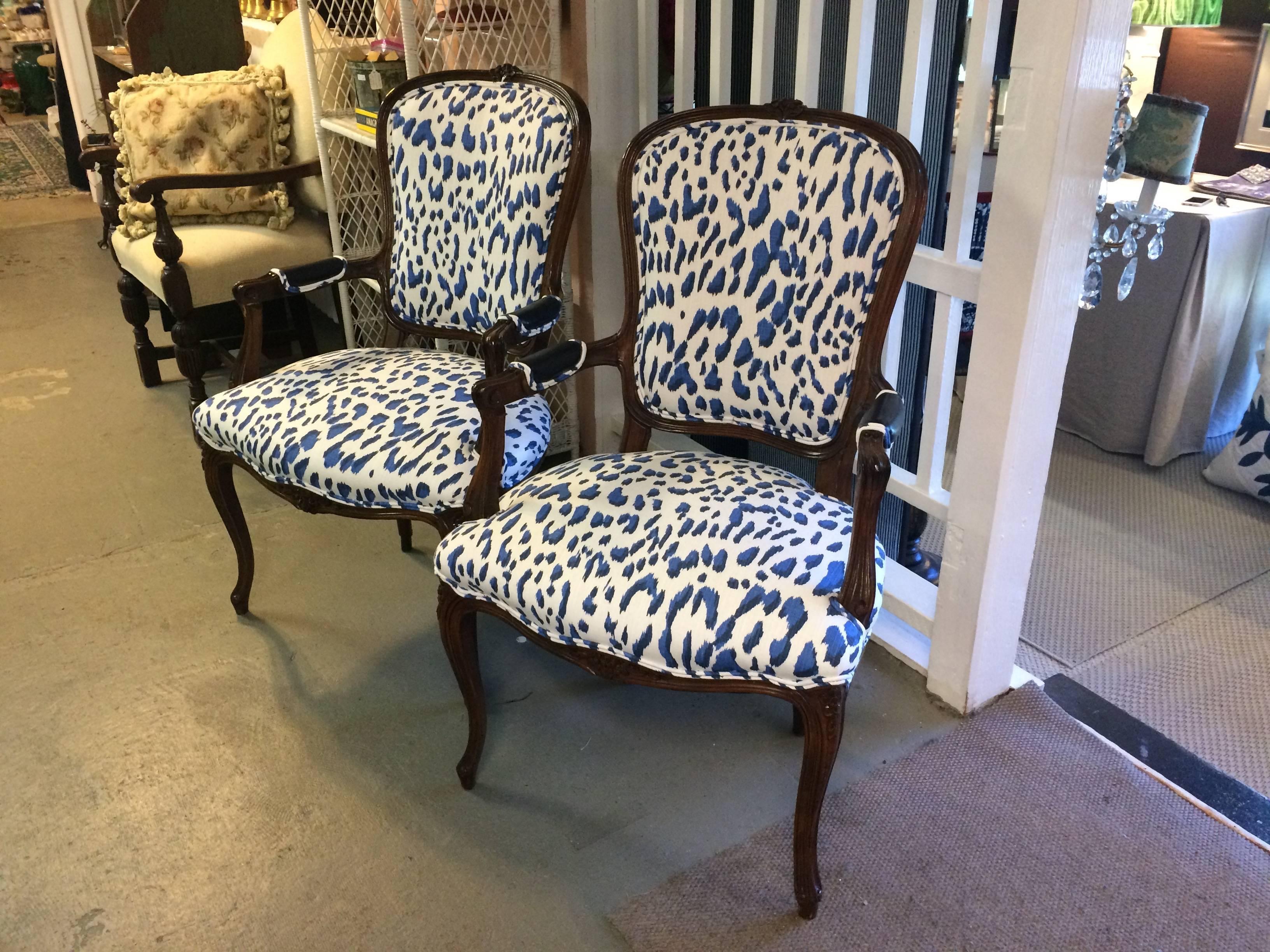 A pair of French style carved walnut vintage bergere chairs contemporized with chic Schumacher blue and white faux leopard linen and handsome arm rests covered in dark navy blue almost black leather.

MJM.