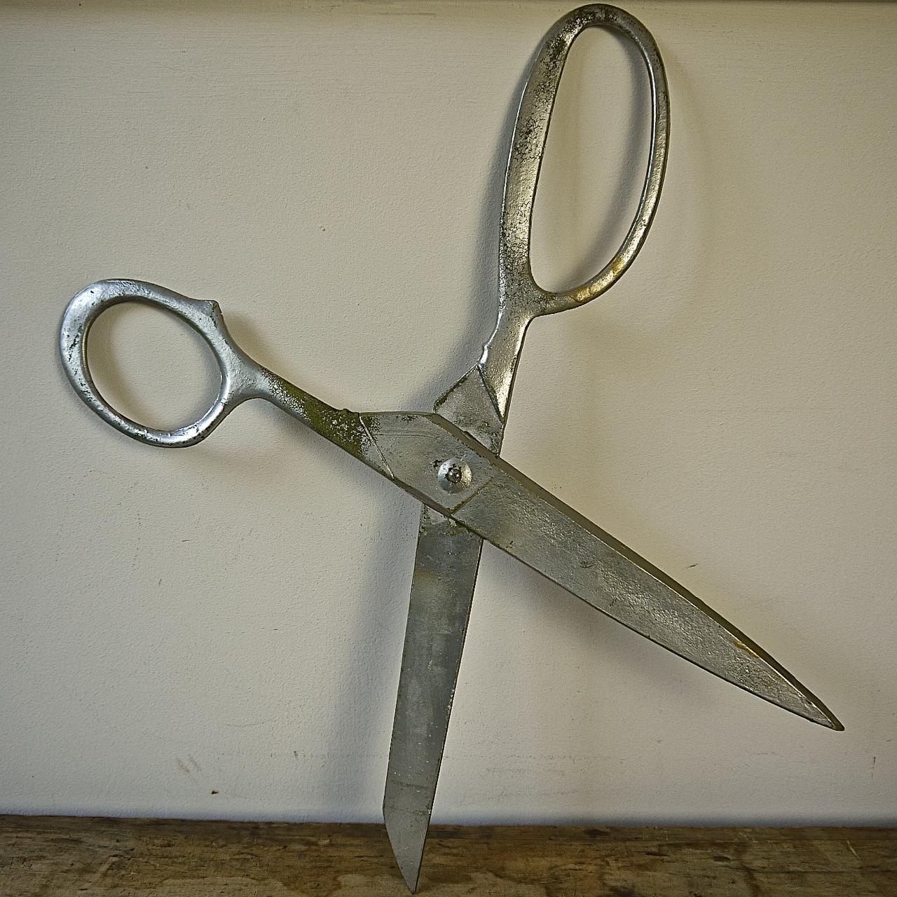 Pair of French light metal scissors once used as a shop sign. They are painted with a silver paint that shows signs of some wear and tear from having been outdoors. With charm and a quirkiness.