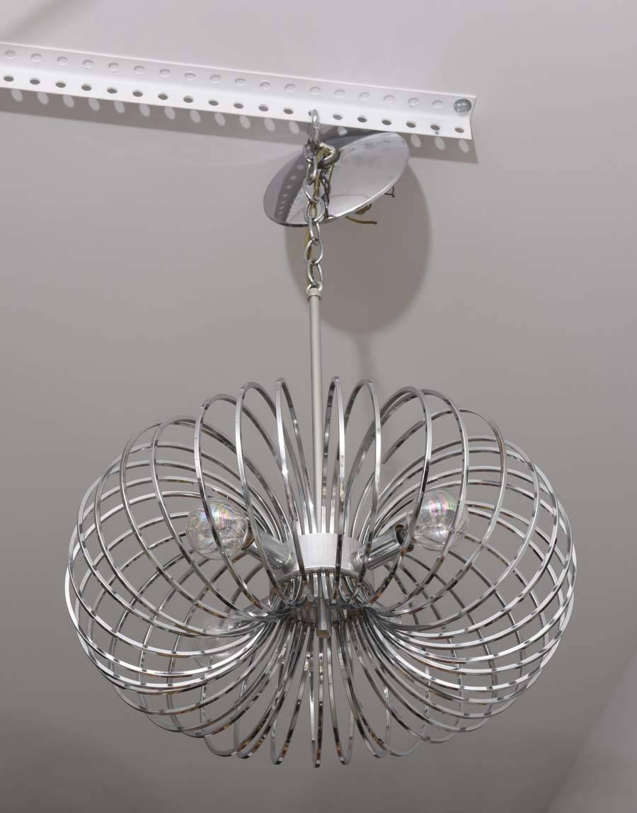 This stylih pair of polished chrome chandeliers date to the 1970s and created by Scolari for Lightolier. 

Note: Each chandelier requires four candleabra based light bulbs.

Note: The main-body of the piece is 7