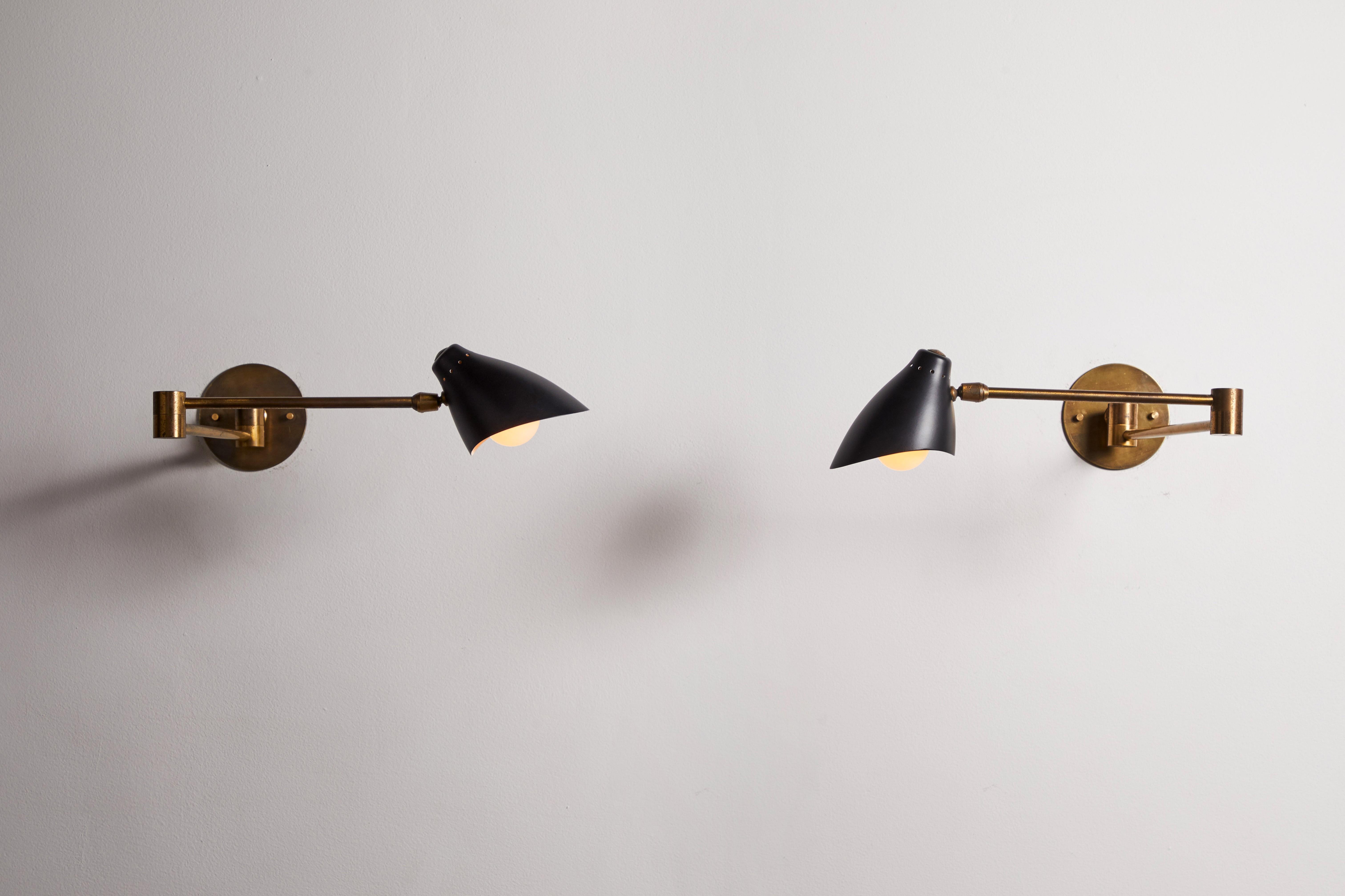 Pair of sconces by Angelo Lelli for Arredoluce. Designed and manufactured in Italy, 1953. Enameled metal, brass. Rewired for U.S. junction boxes. Arms adjust via a triple joint structure. Shades adjust to various positions via ball joint. Custom