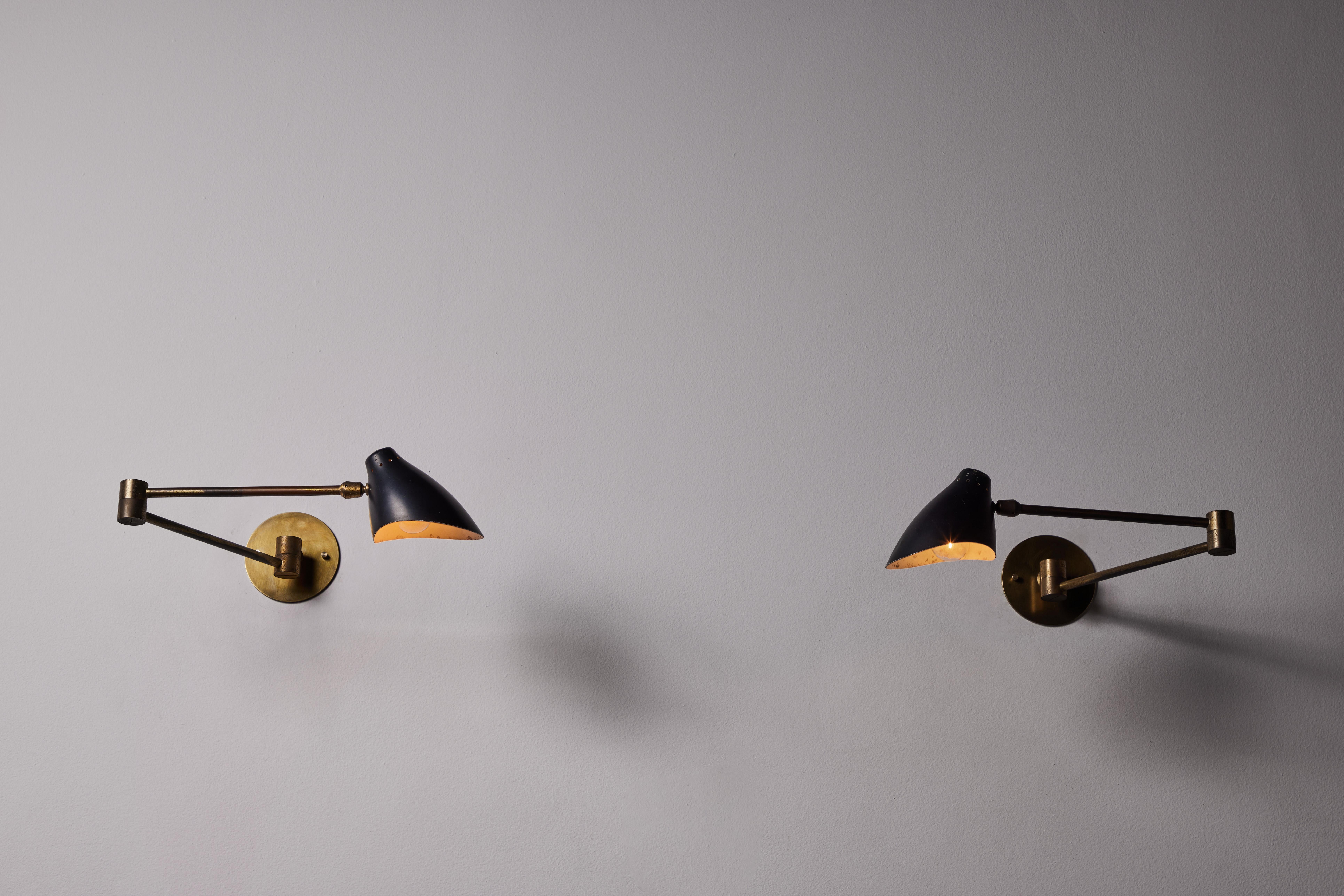 Pair of sconces by Angelo Lelli. Designed and manufactured in Italy, circa 1950s. Enameled aluminum, brass. Custom brass backplates. Rewired for U.S. standards. Arms and shades adjust positions we recommend one E26 40w bulb per sconce. Bulbs